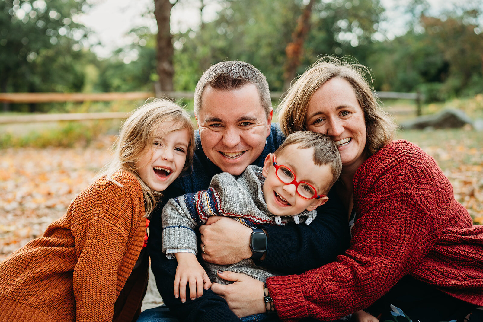 family of four put heads close together and smile at camera