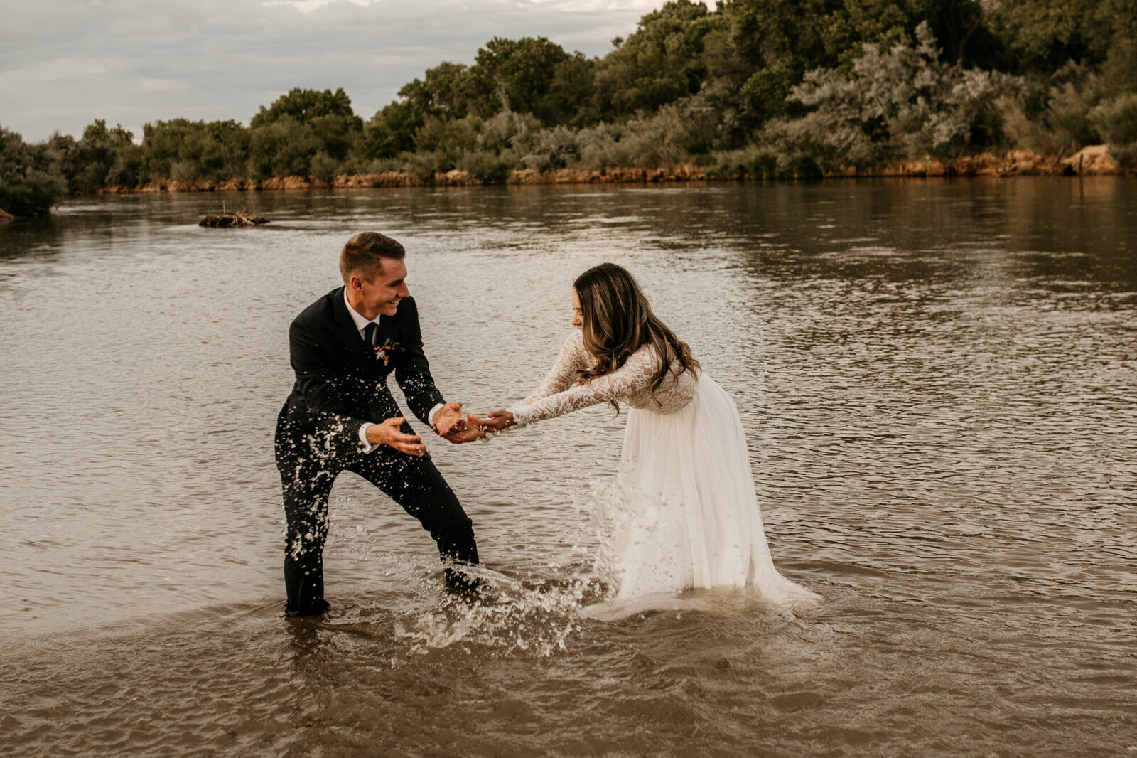newly wedds splashing water at each other in a river