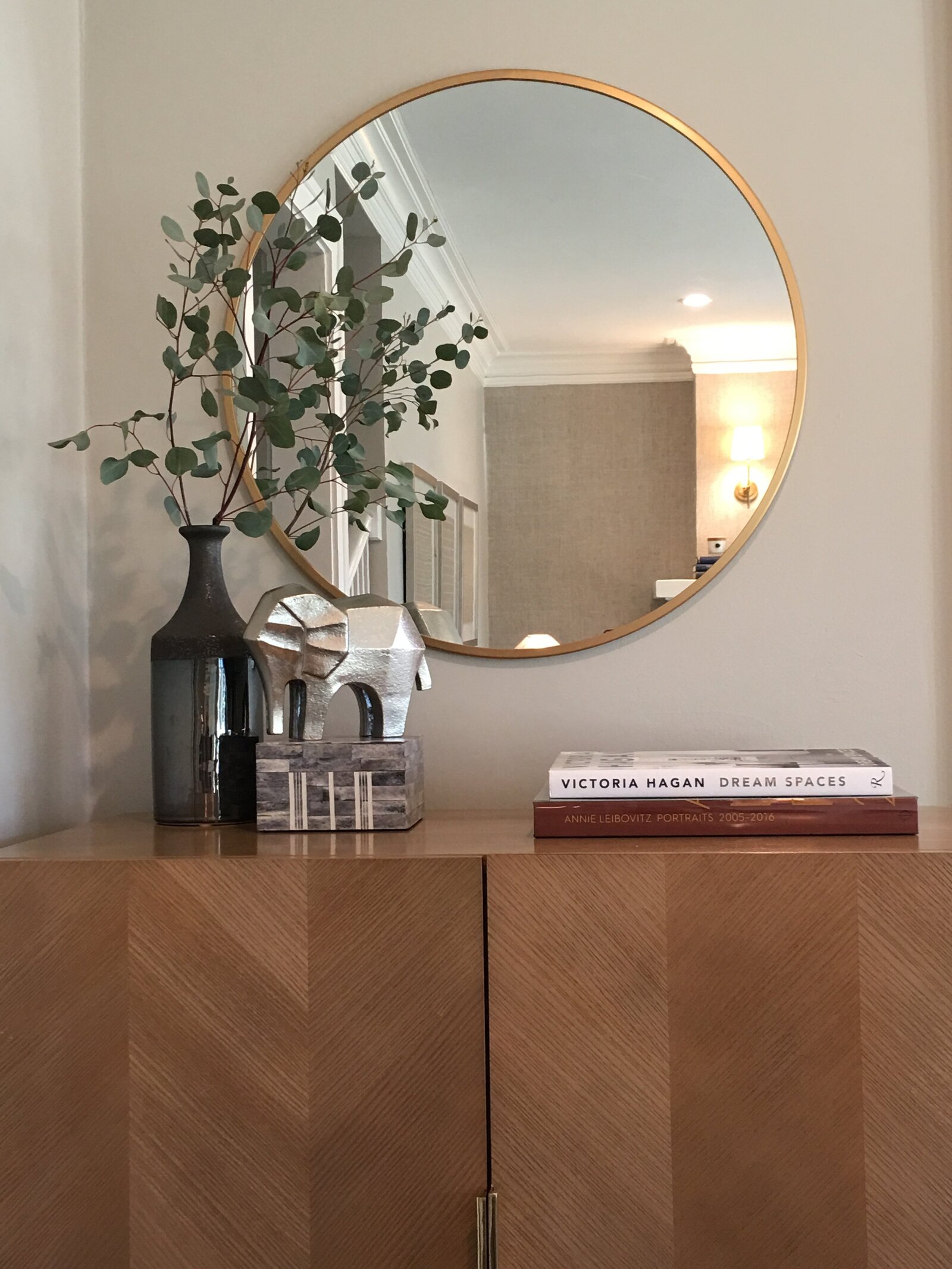 Round gold mirror and midcentury wooden cabinet