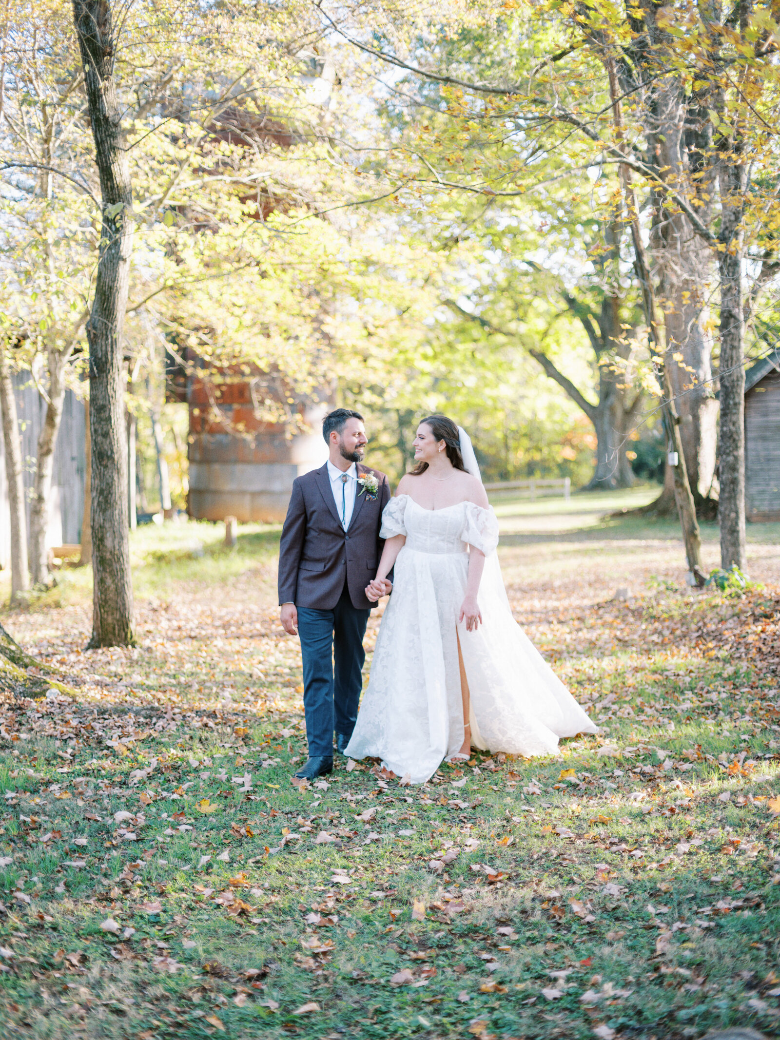 A bride and groom walking between trees in Hillsborough NC