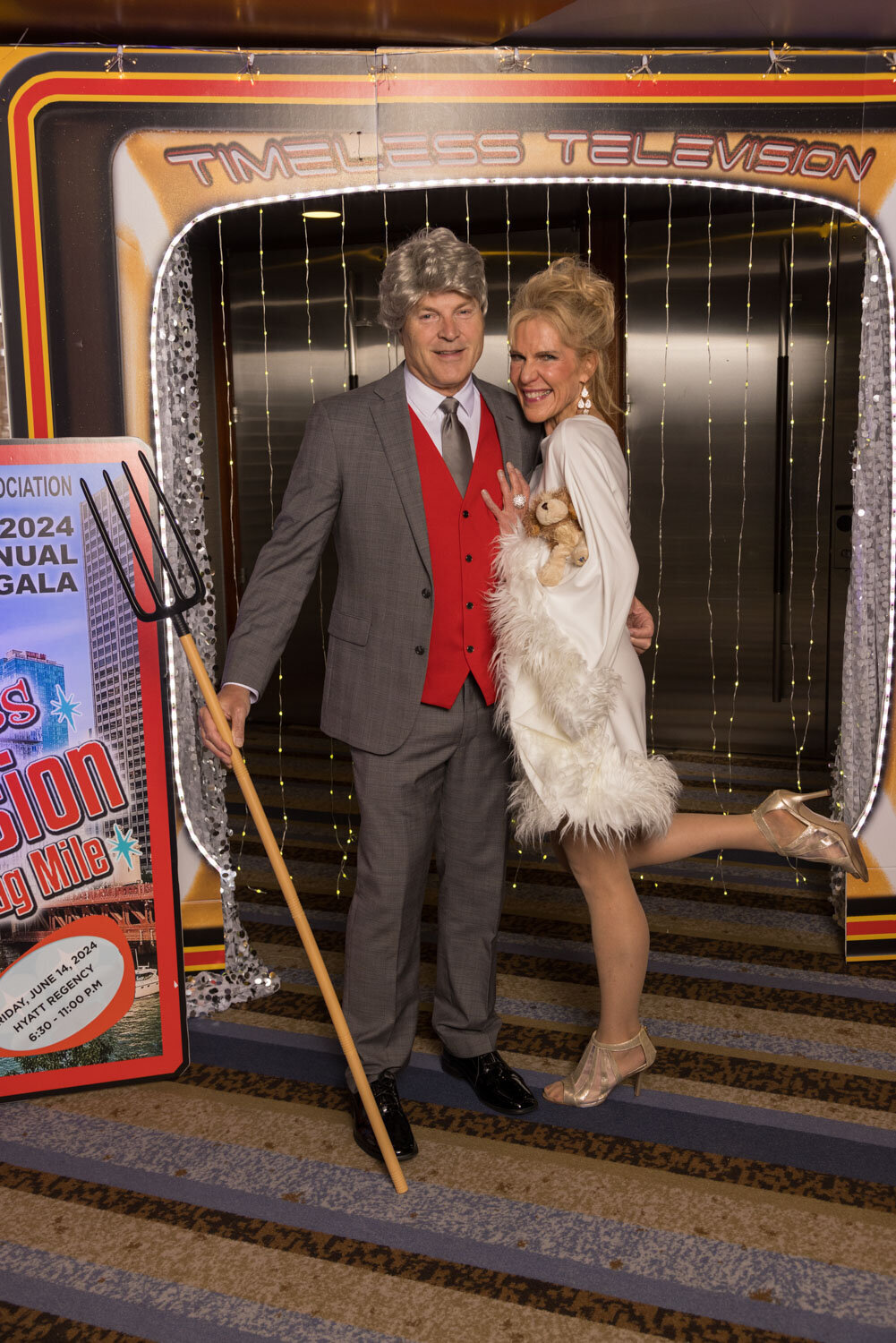 Couple in costume posing in front of a retro photo booth backdrop