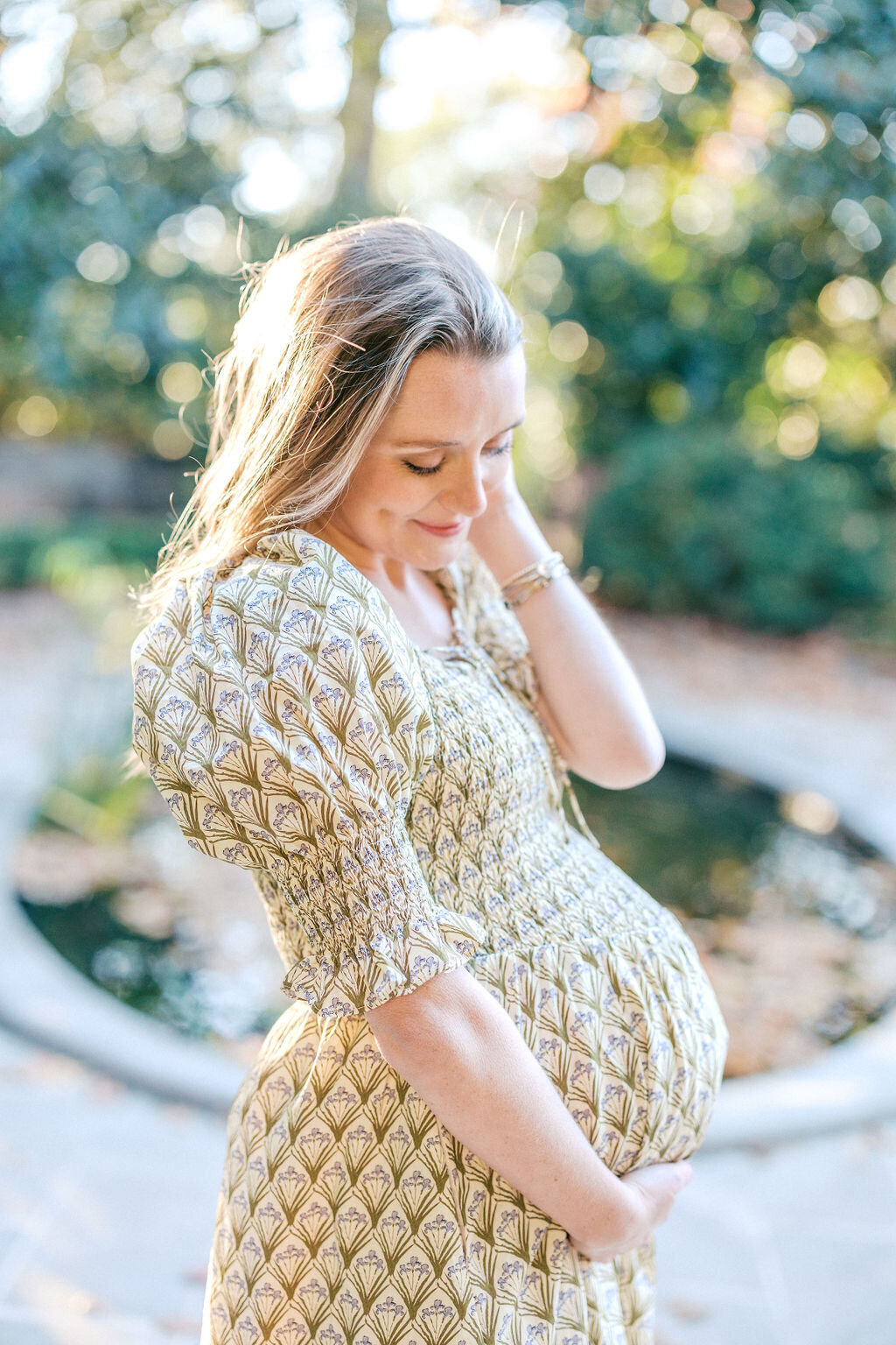 Woman smiles holding baby bump outside Athens City Hall