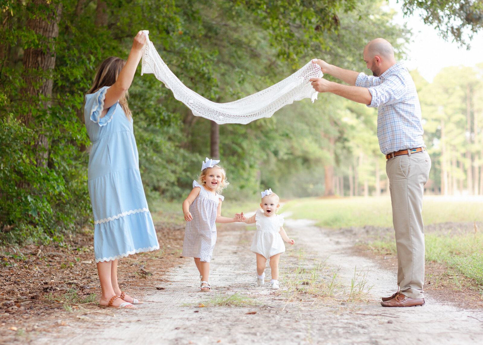 Family of 4 having fun during their photoshoot by playing London bridge with their daughters