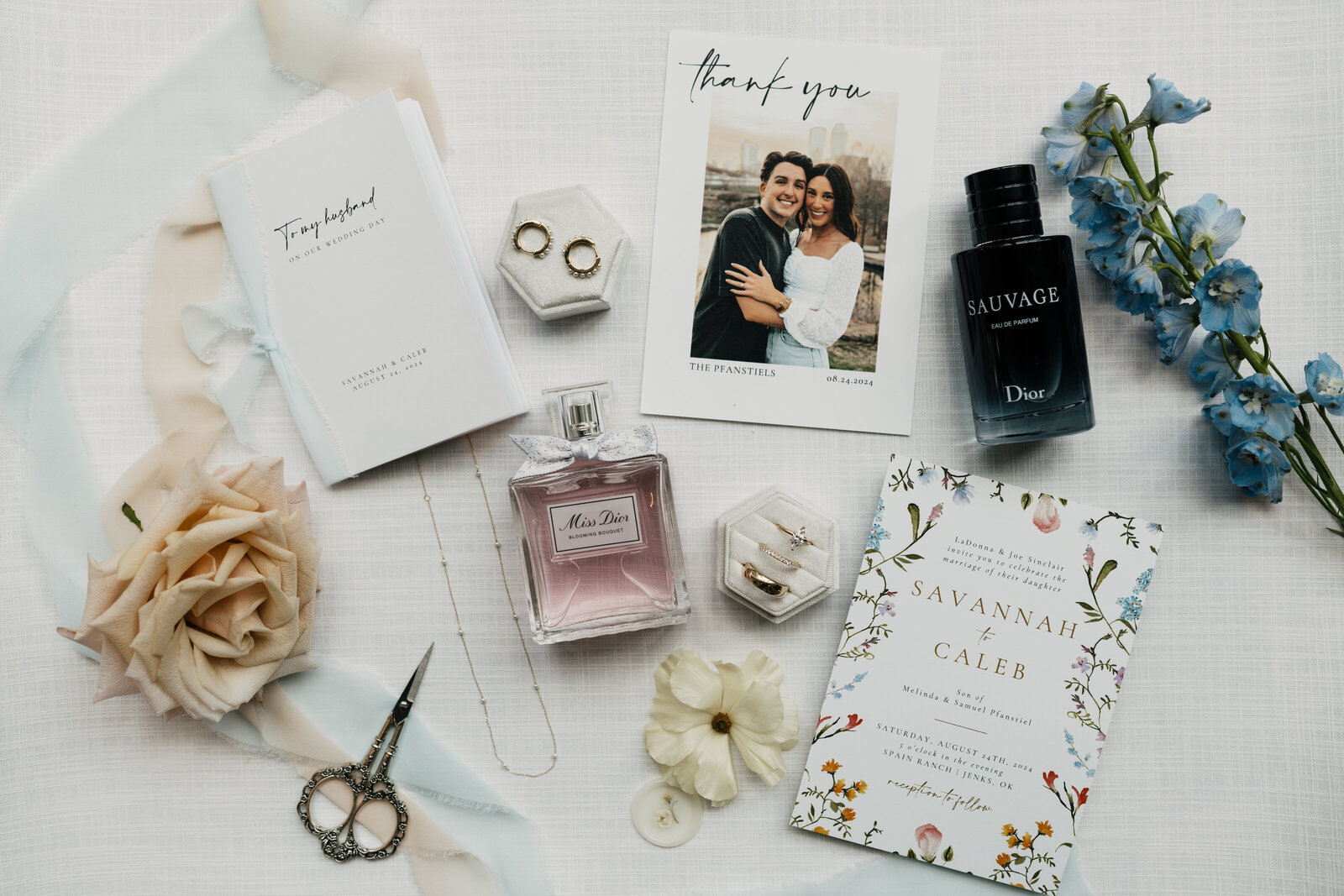 Flat lay of wedding rings, invitation suite, and floral bouquet in Oklahoma wedding at Spain Ranch.