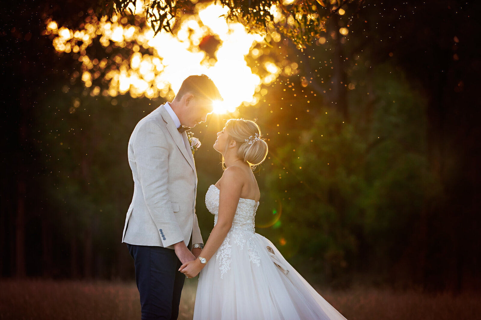 husband and wife holding hands at sunset wrapped in beautiful golden light