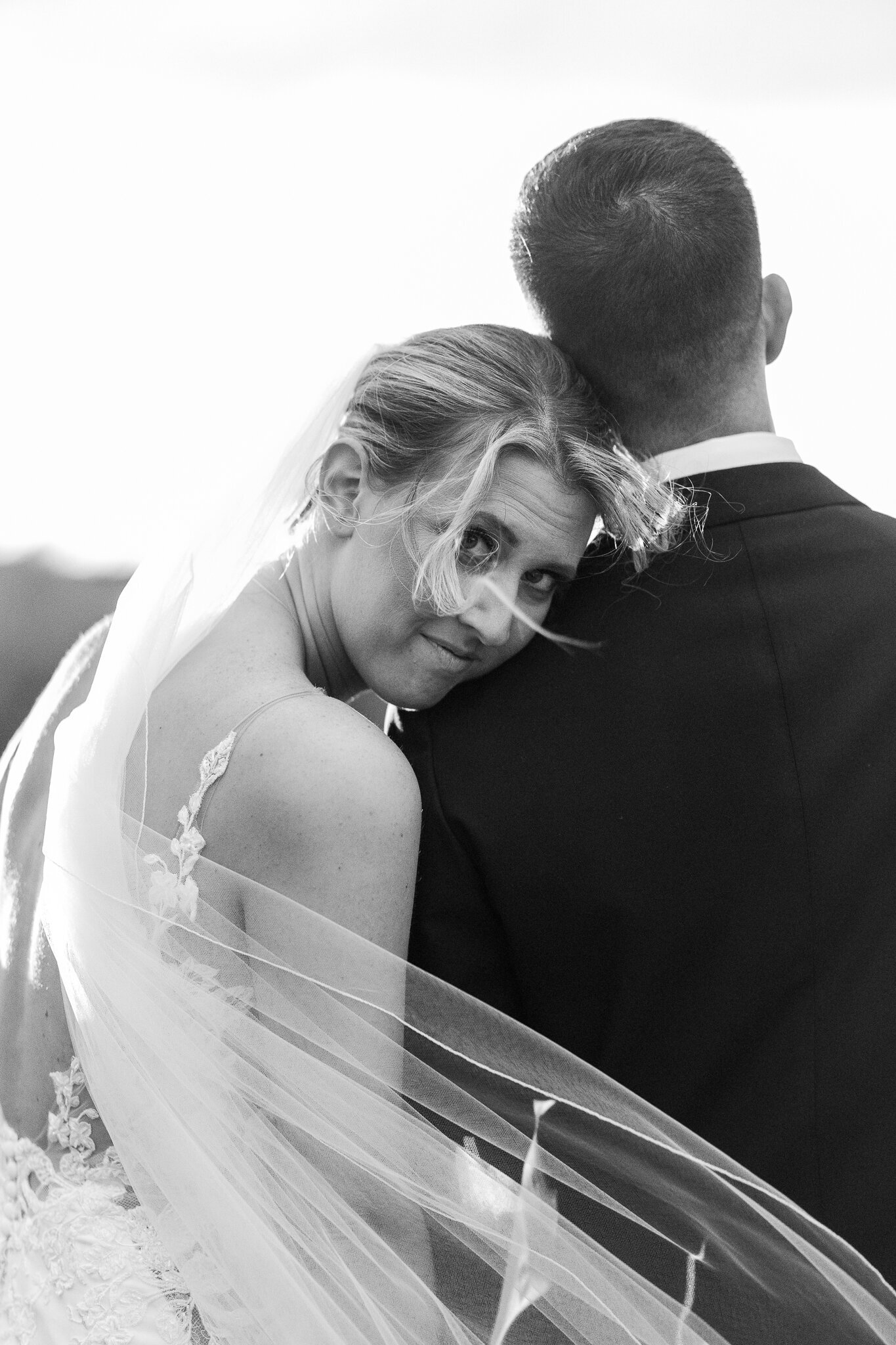  Close-up black and white photo of bride resting on groom’s shoulder with soft expression

