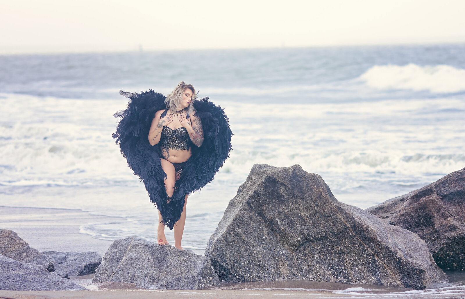 Woman on beach woth black angel wings in heart shape