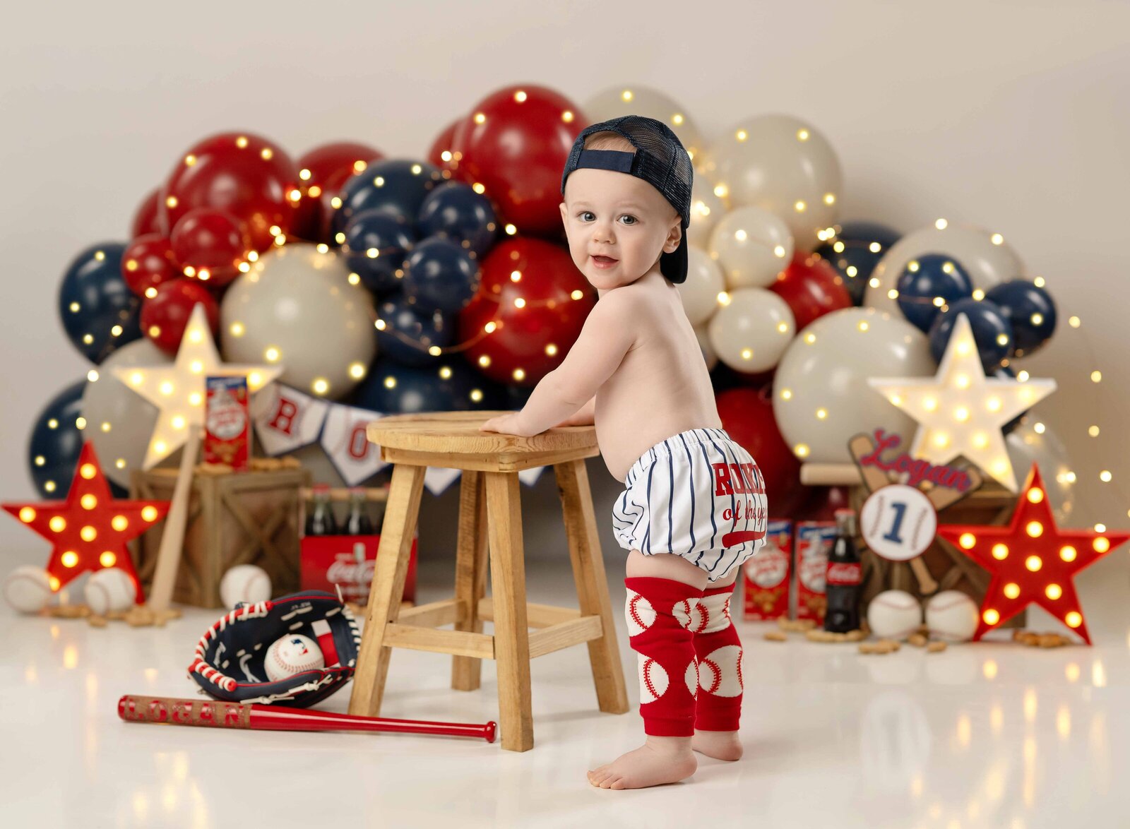 Rookie of the year cake smash balloon garland and props with baby standing up and holding onto a stool.