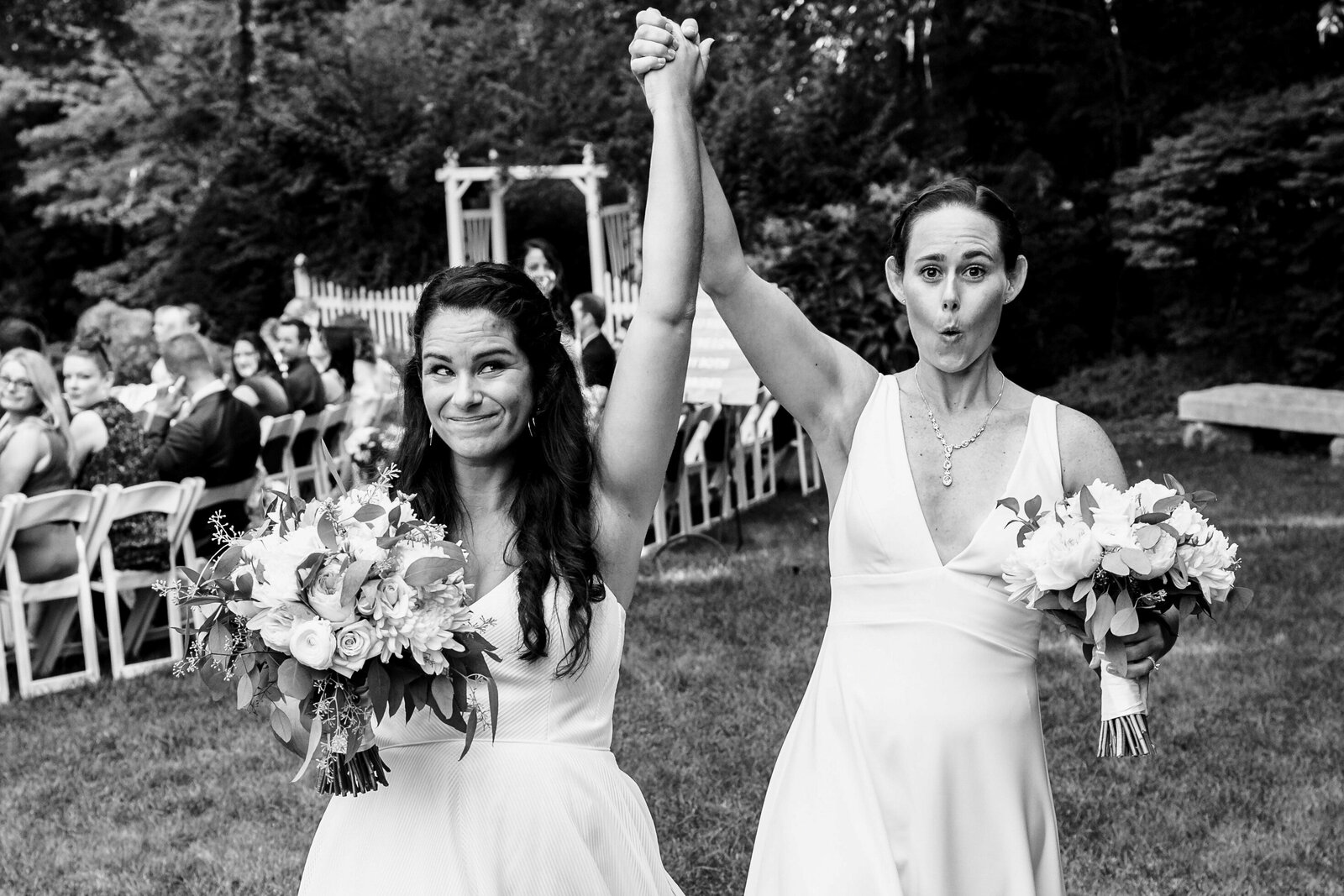black and white image of two brides making fun faces during recessional
