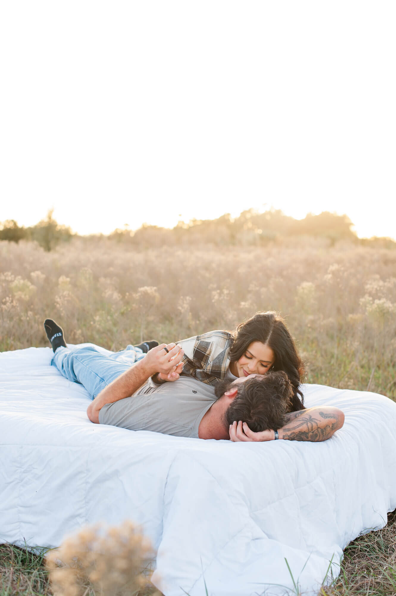 Orlando couple lays on an air mattress cuddling in a tall grass field
