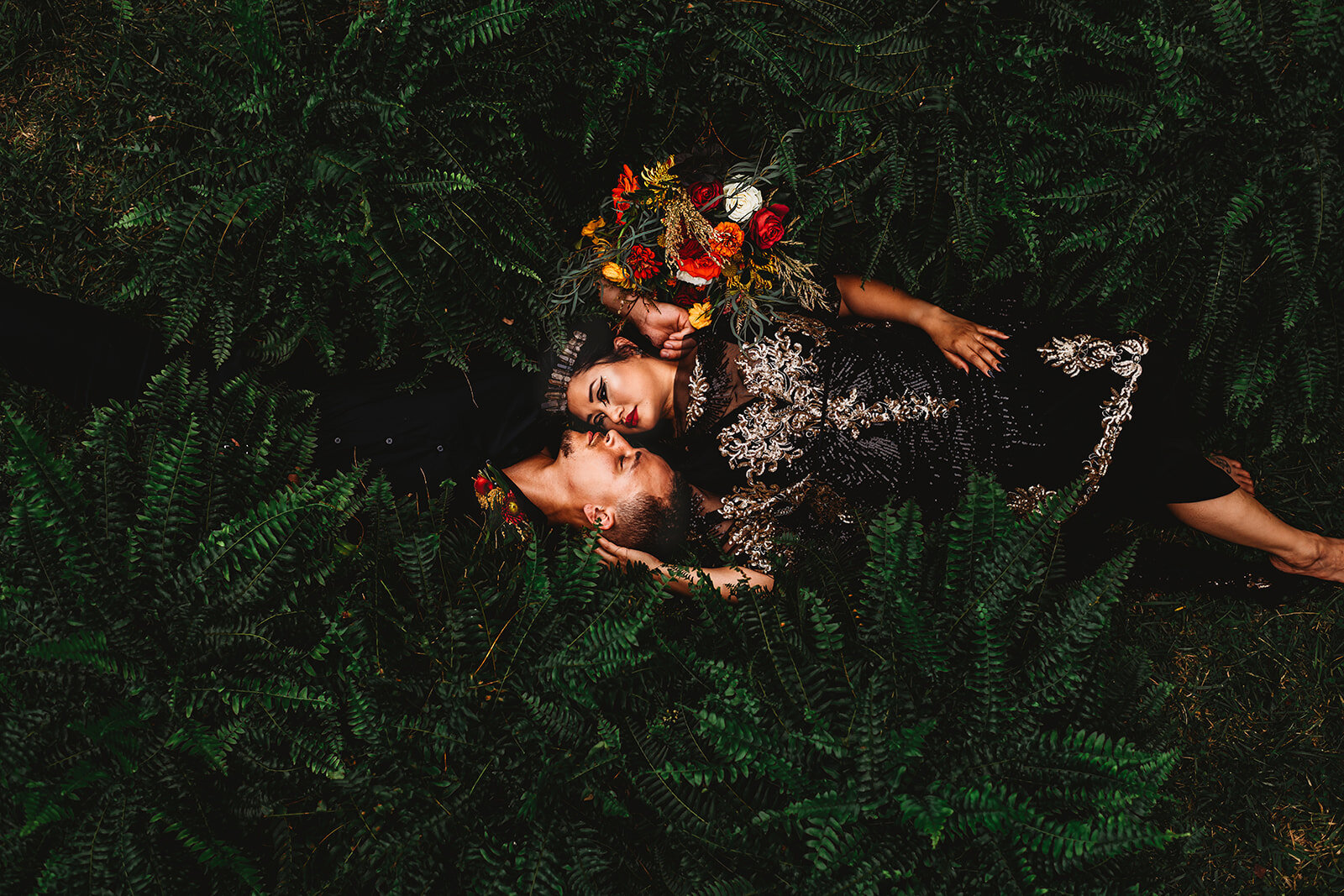 Baltimore photographers captures unique wedding photos with bride and groom laying together in a field of ferns while they embrace each other