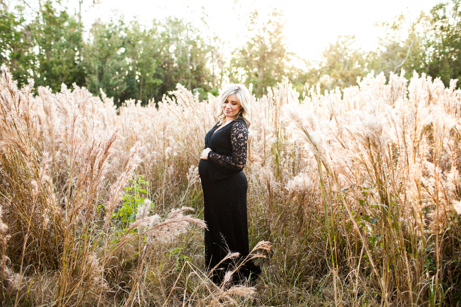 Maternity pictures in long black dress in field of wheat