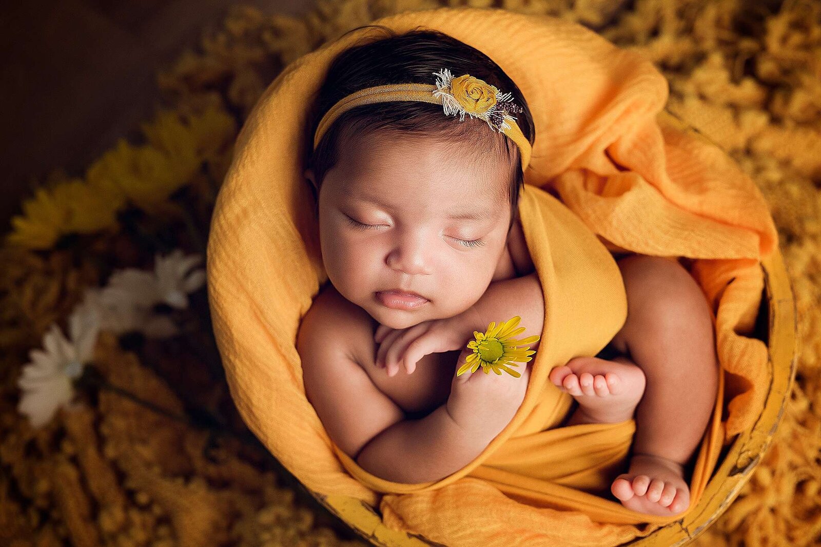 A peaceful newborn girl sleeps in a basket adorned with a flower, captured by Bia Schaefer, Winter Garden newborn photographer.