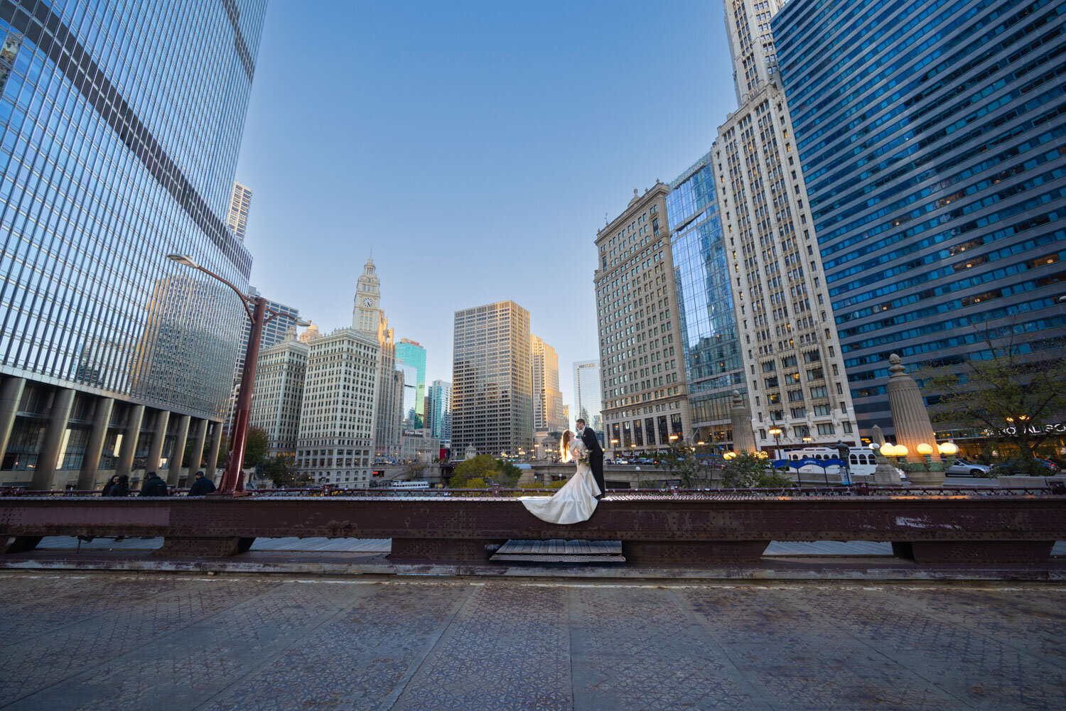 A bride and groom are posing for a picture in front of a city skyline