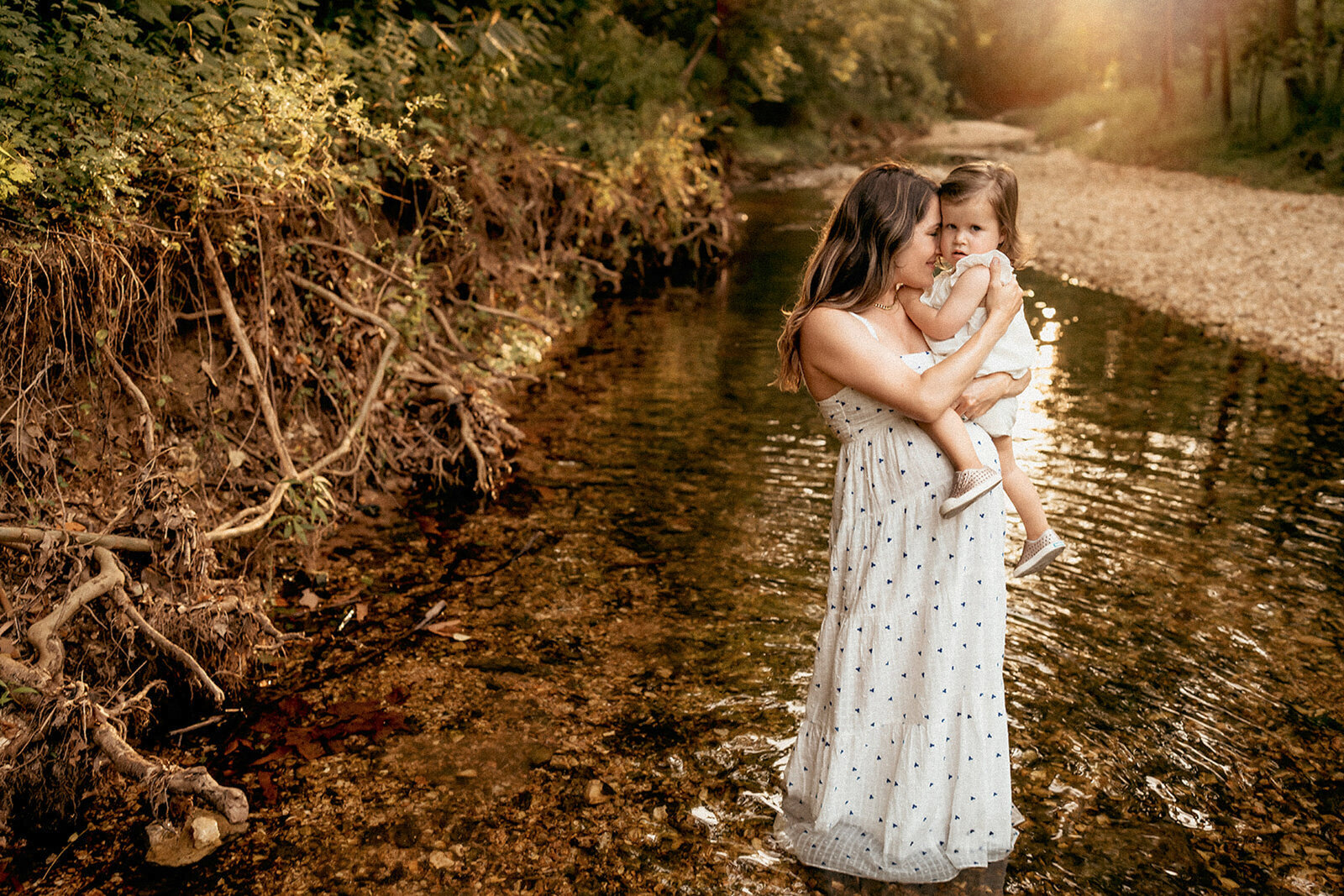 mom standing in a creek with daughter
