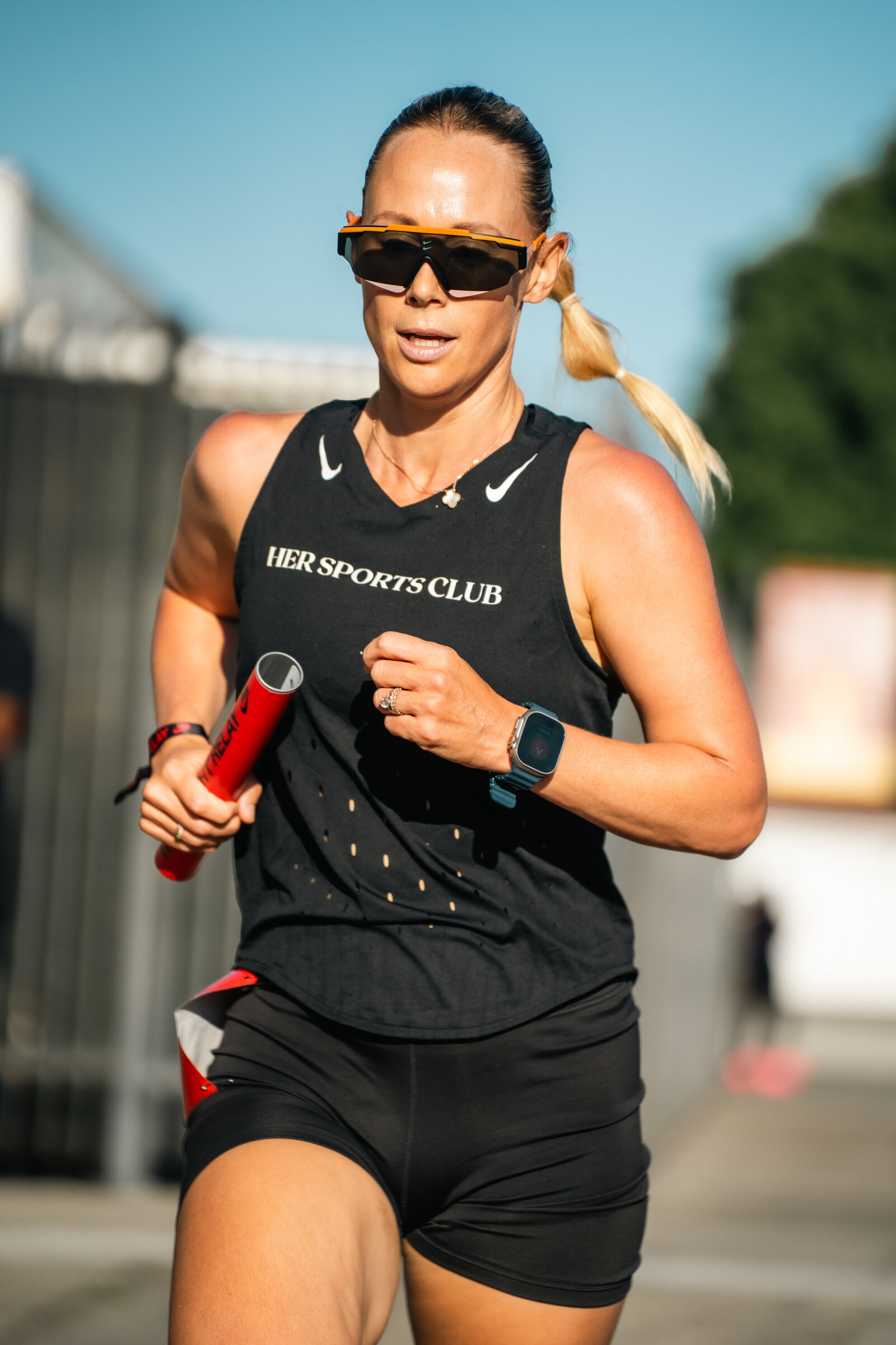 HER Sports Club runner holding a relay baton during a race