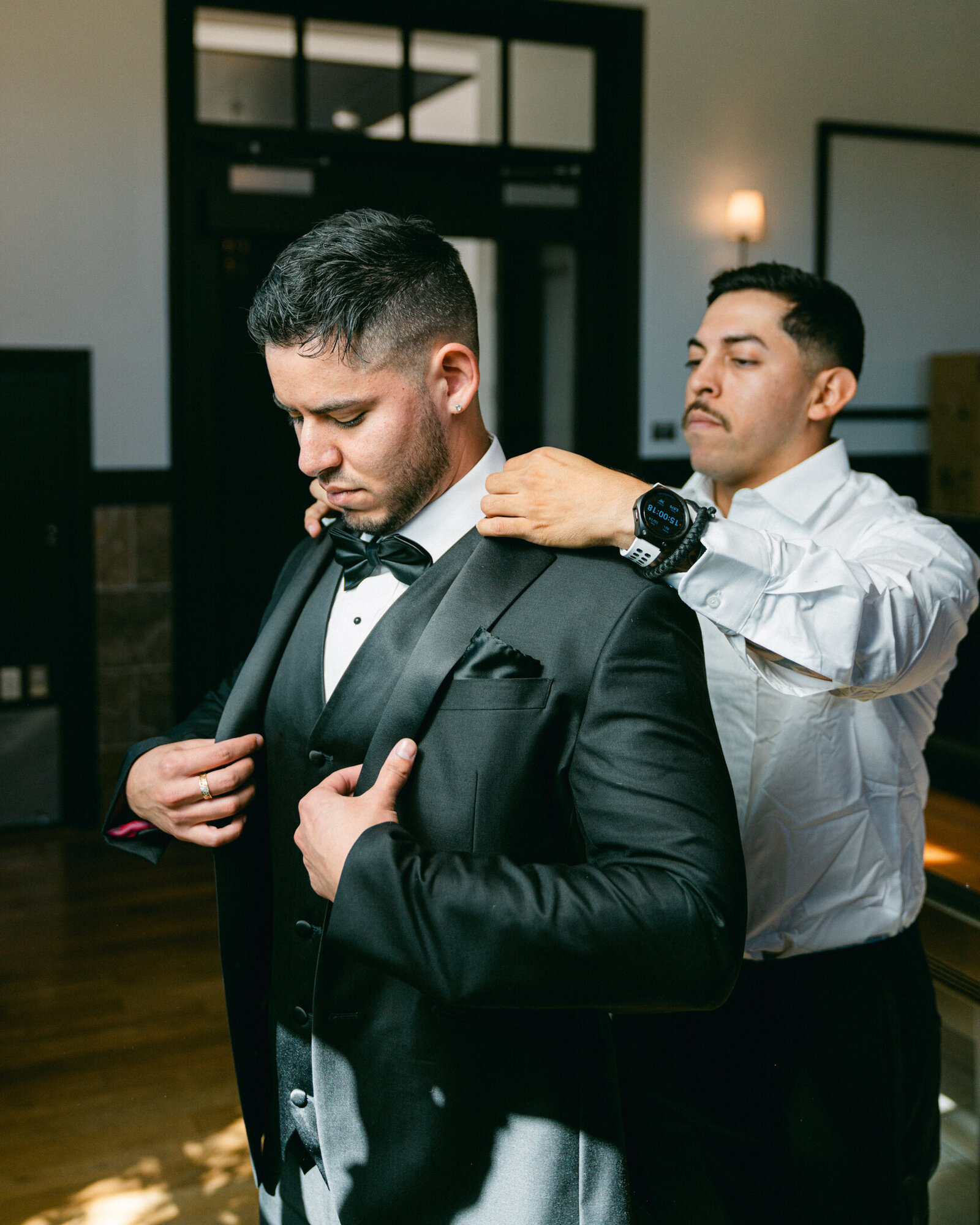 Best Man helps Fort Worth Groom get ready for his wedding by helping him put on his tuxedo