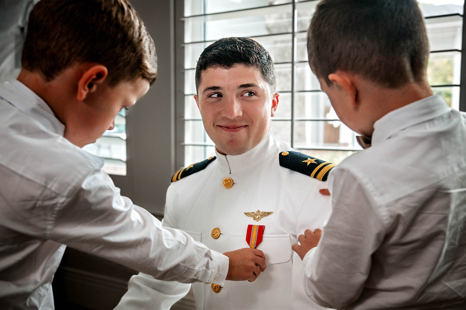 A groom in his Navy uniform, preparing for his wedding ceremony, captured by CMH Studios in a military wedding in San Antonio.