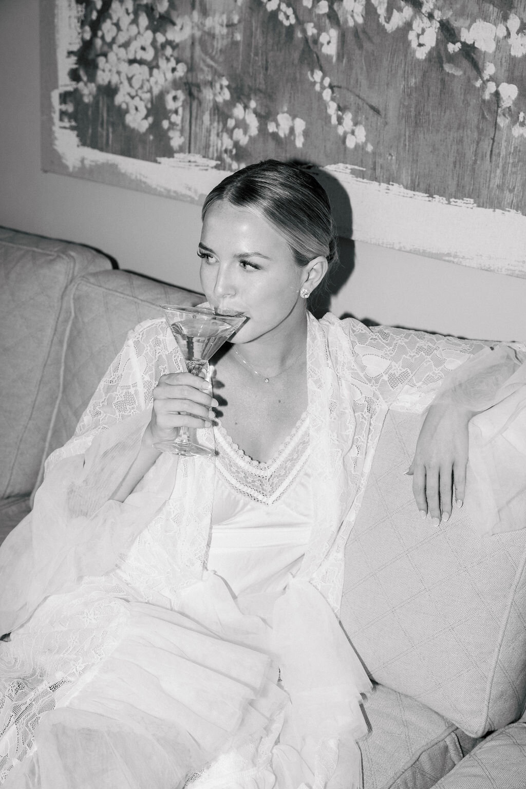 Bride sips from martini glass in white robe