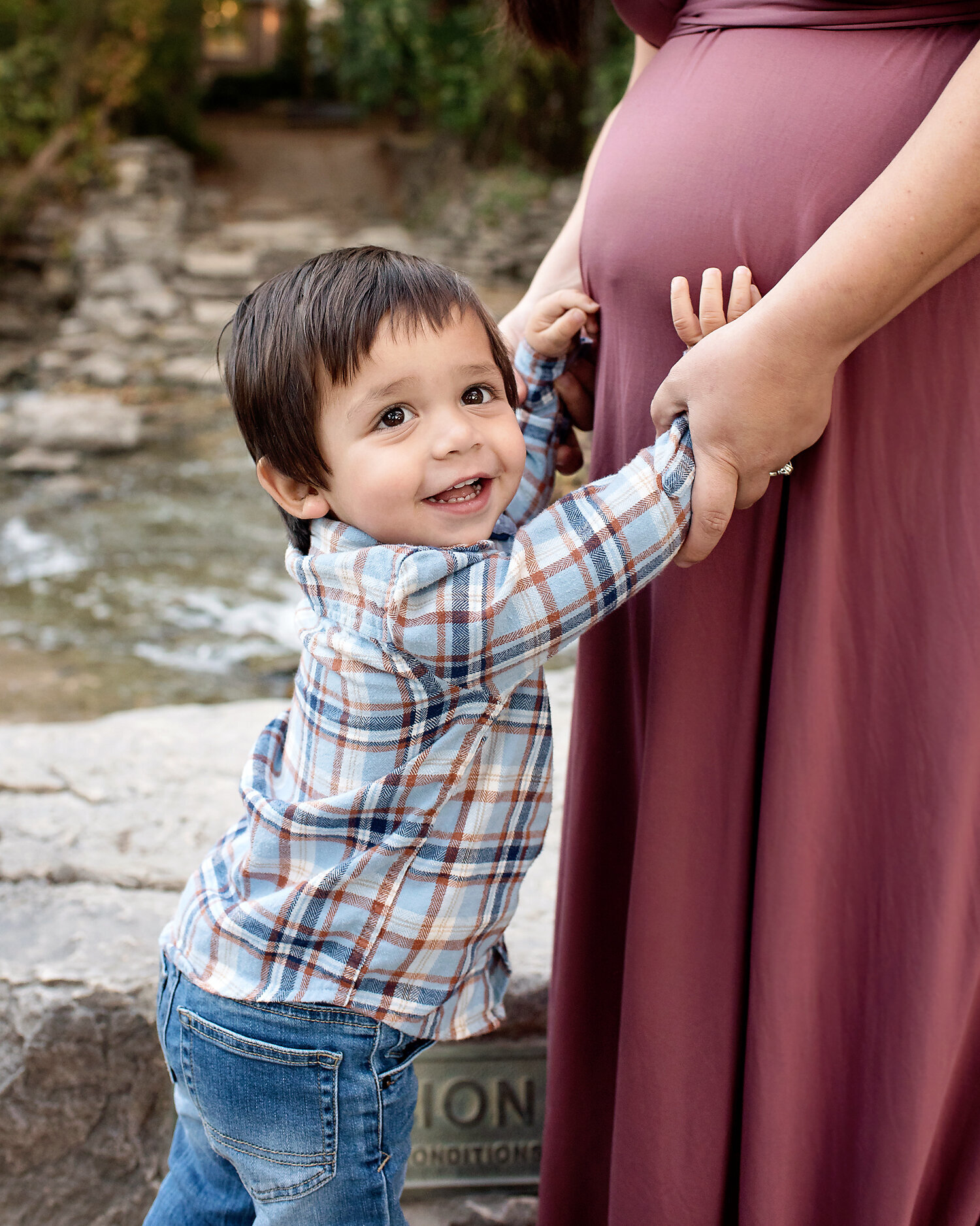 Young boy with his hands on his mother's pregnant belly at her maternity session at Prairie Creek Park.