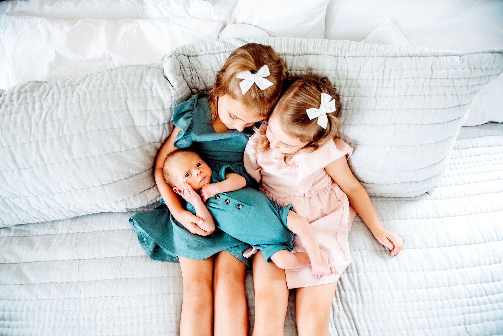 two older sisters holding their baby brother
