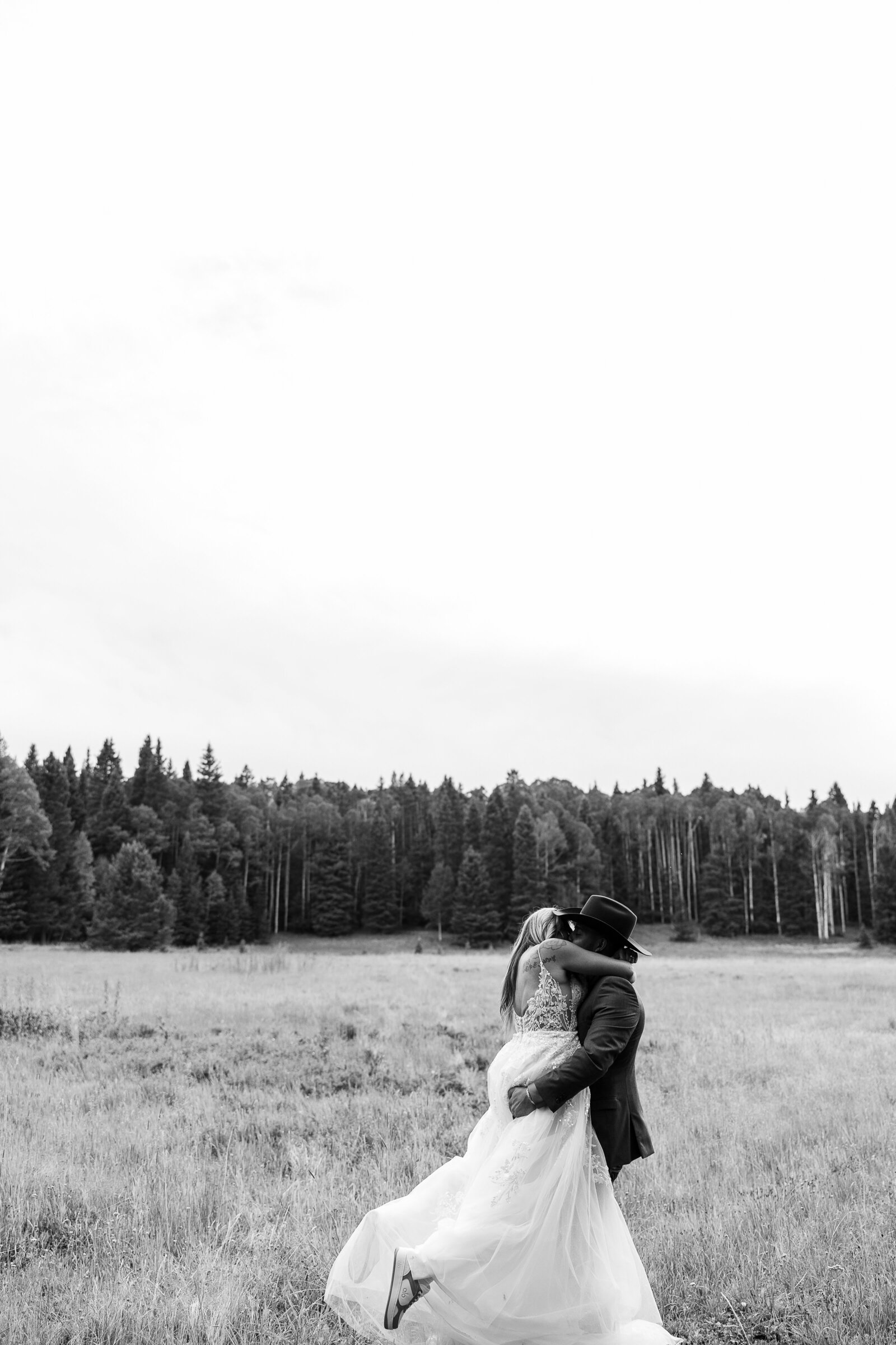 Groom lifts and spins his bride in this black and white capture of the newlyweds