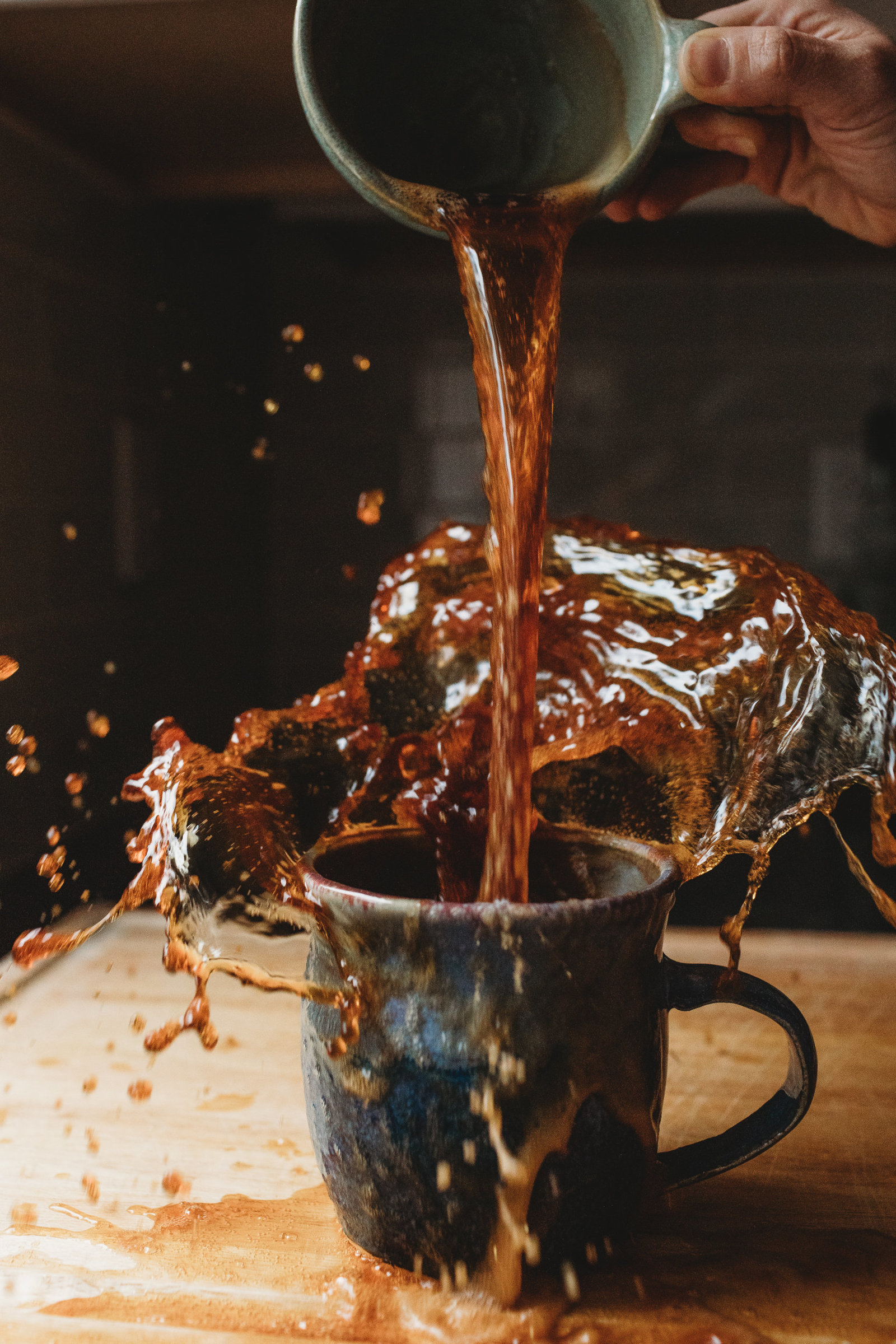 someone messily pours coffee from one mug to the other with a big splash