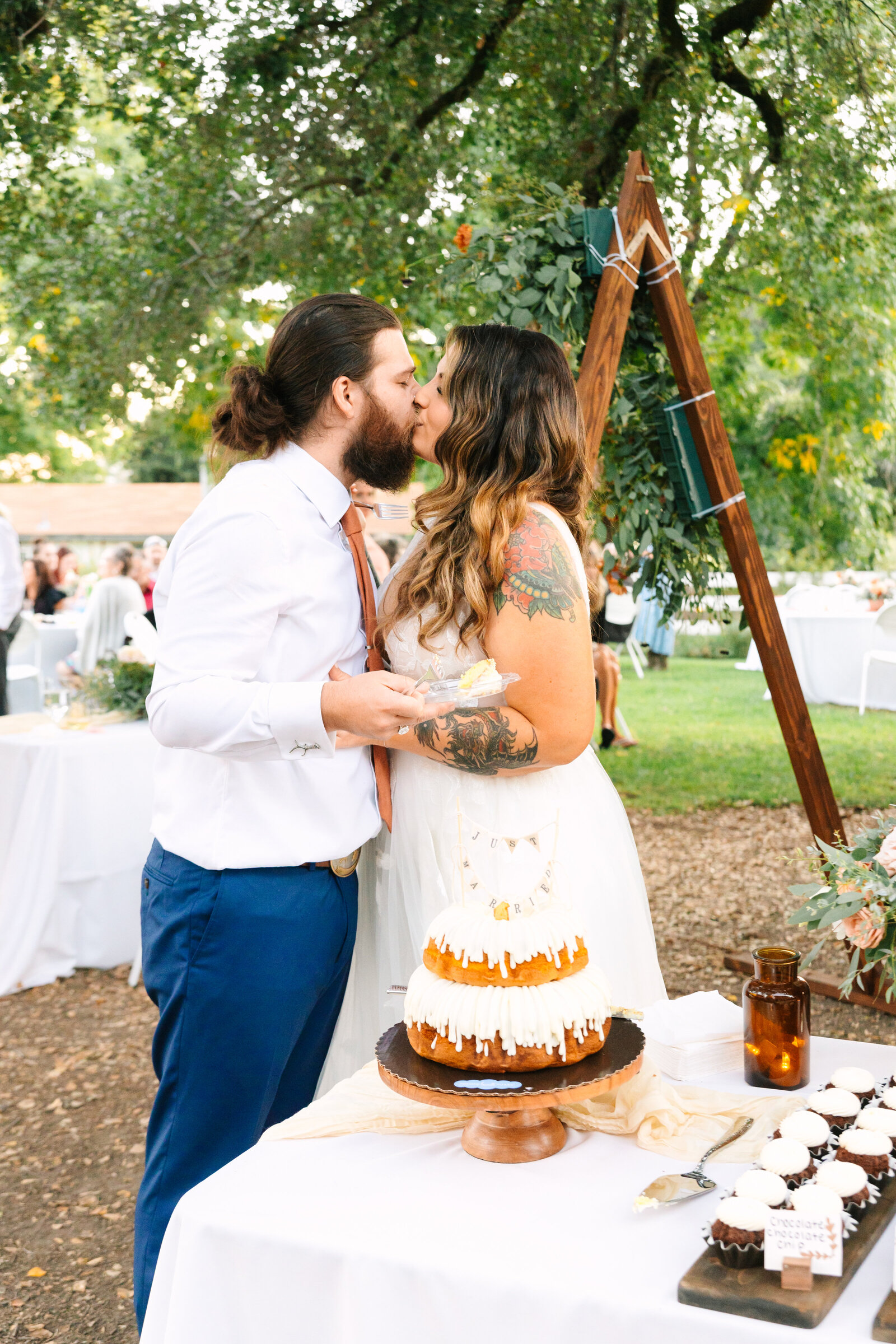 Tattoo bride and groom at their colorful wedding reception in Santa Cruz, California. Cutting the wedding cake.
