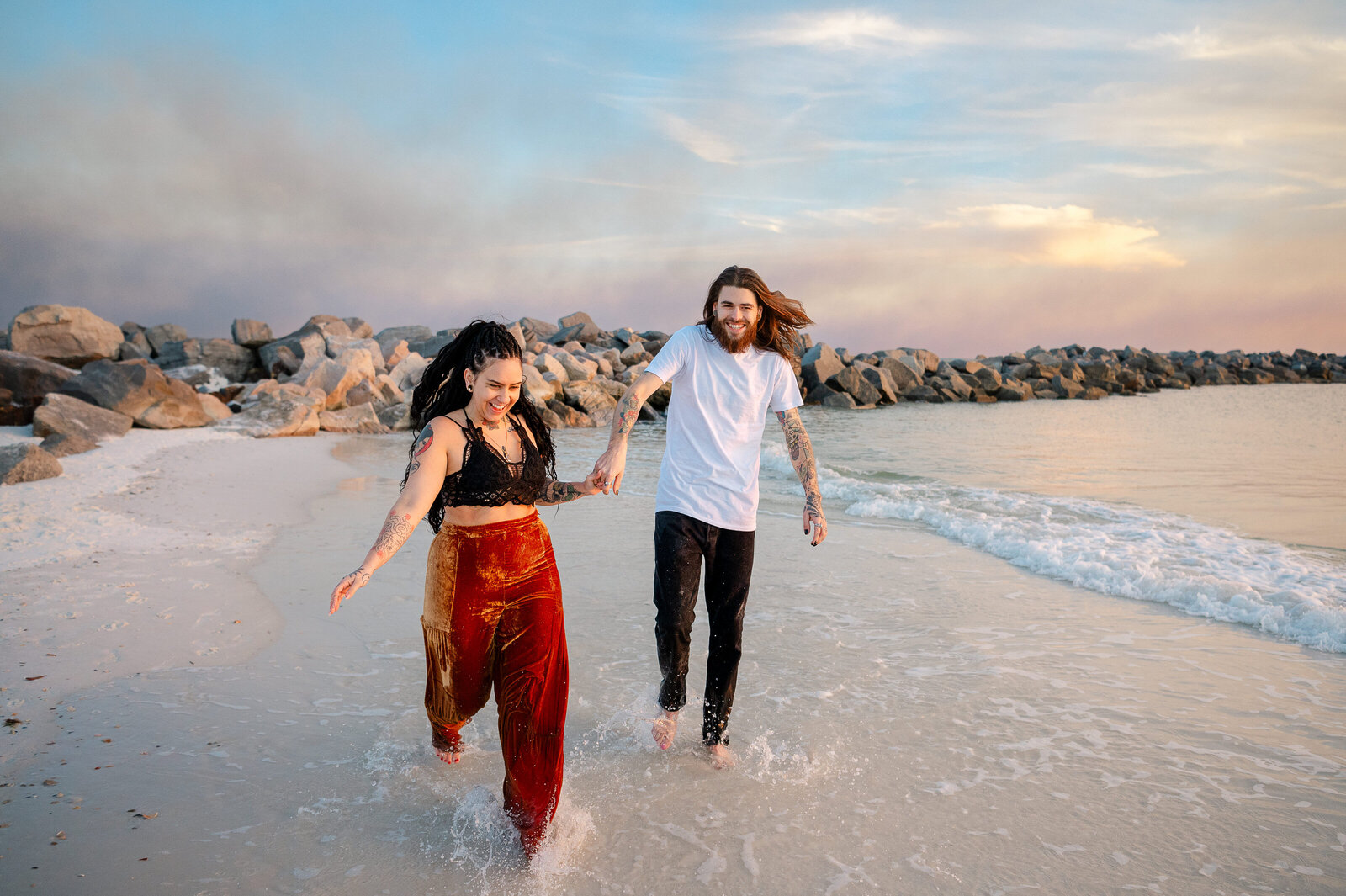 Couple runs down beach laughing together during their engagement photos