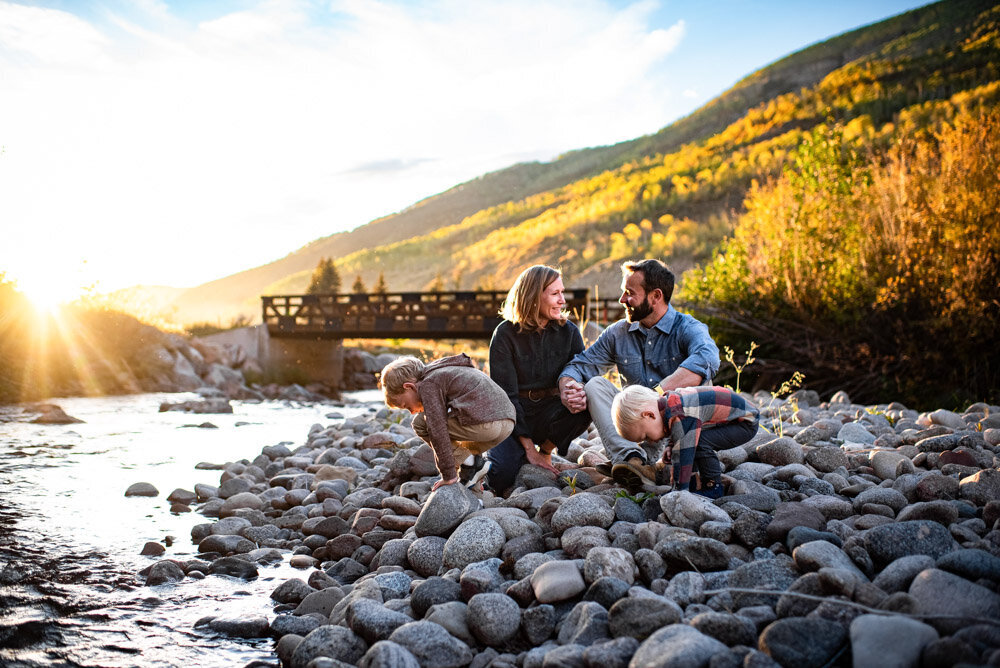 A family sits by the river in Vail, Colorado and throws rocks in the river