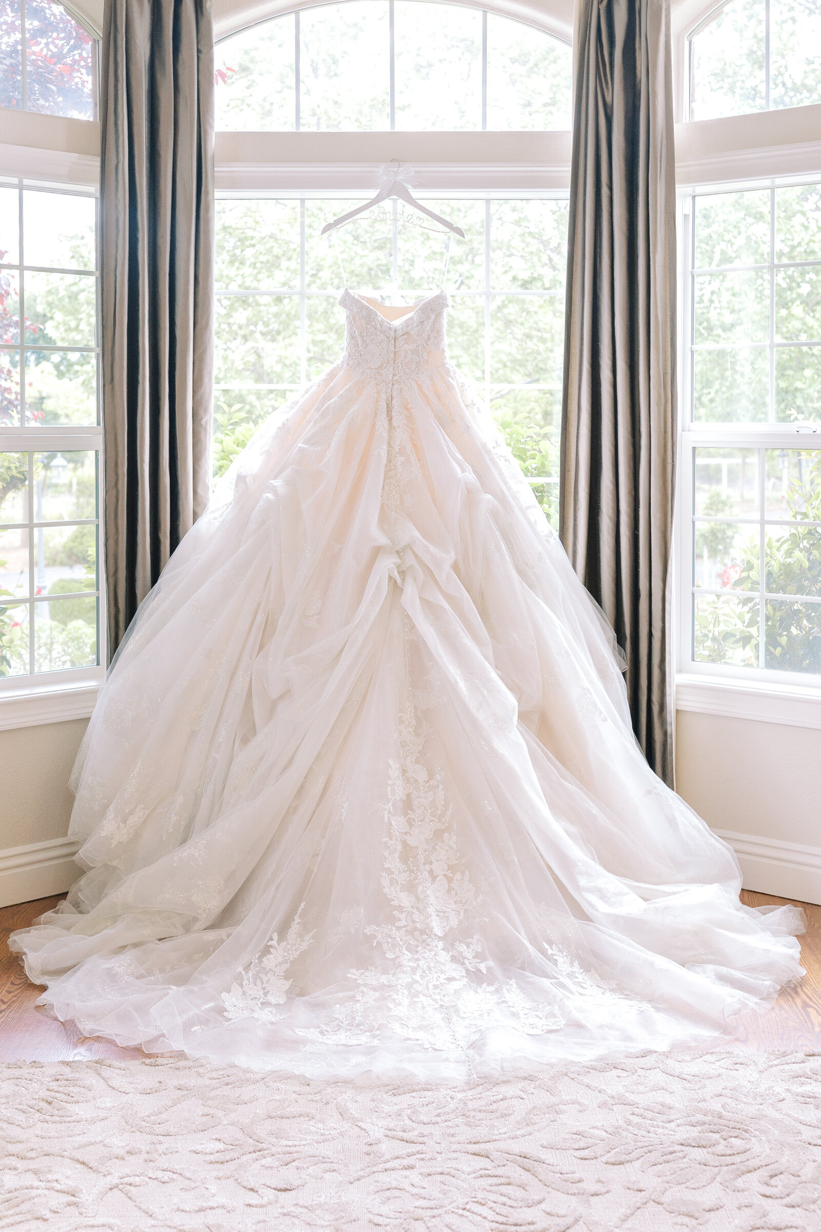 sacramento wedding photographer captures bridal gown hanging in a window at Wolfe Heights in a bridal suite indow