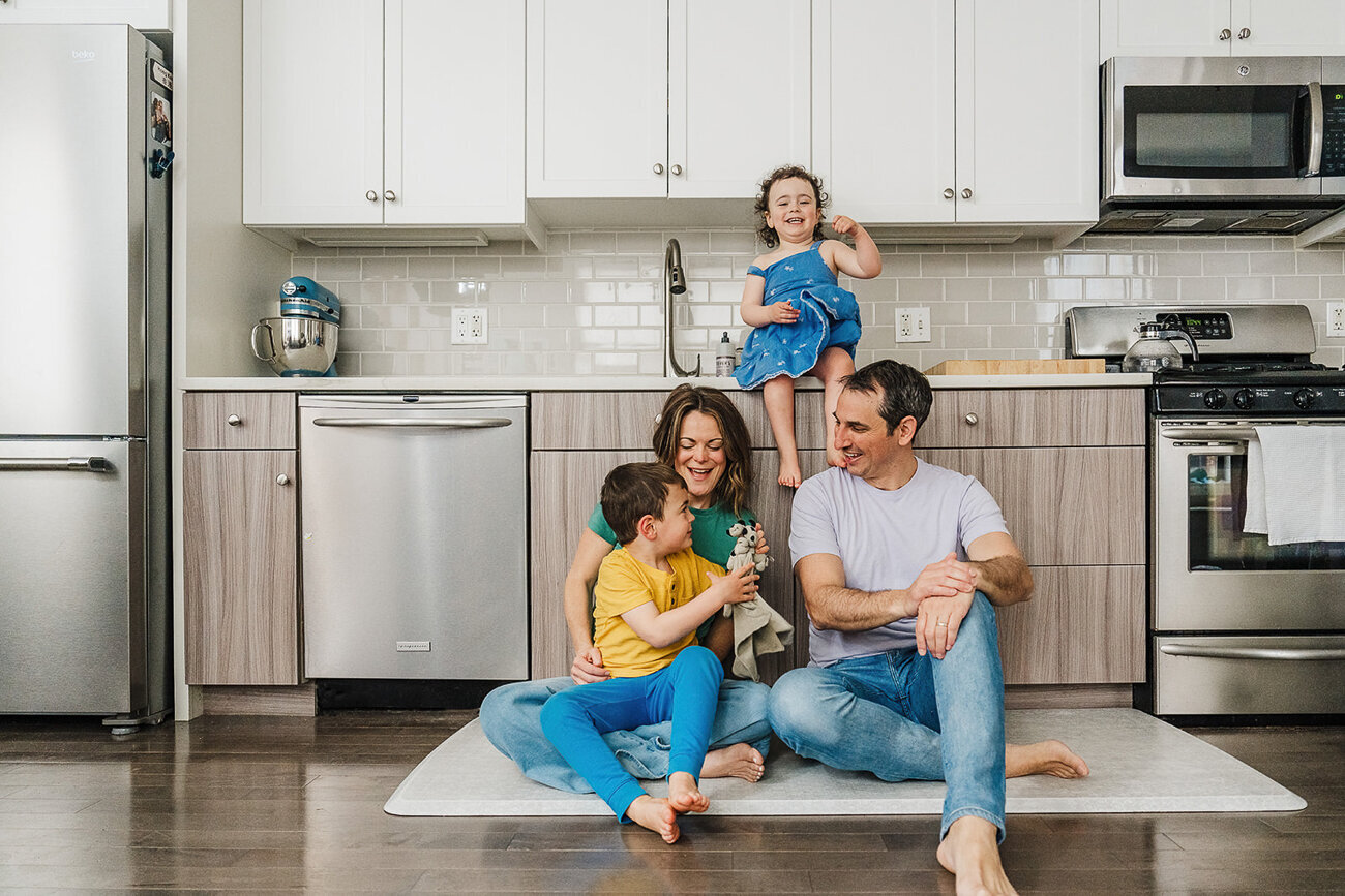 family laughs together on the floor of kitchen in boston
