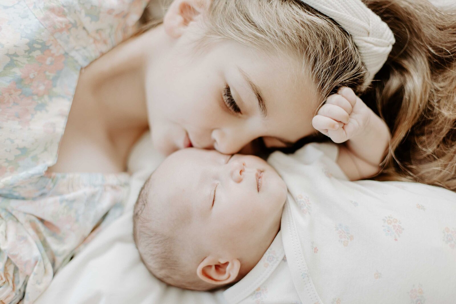 Sister kisses newborn sister photography
