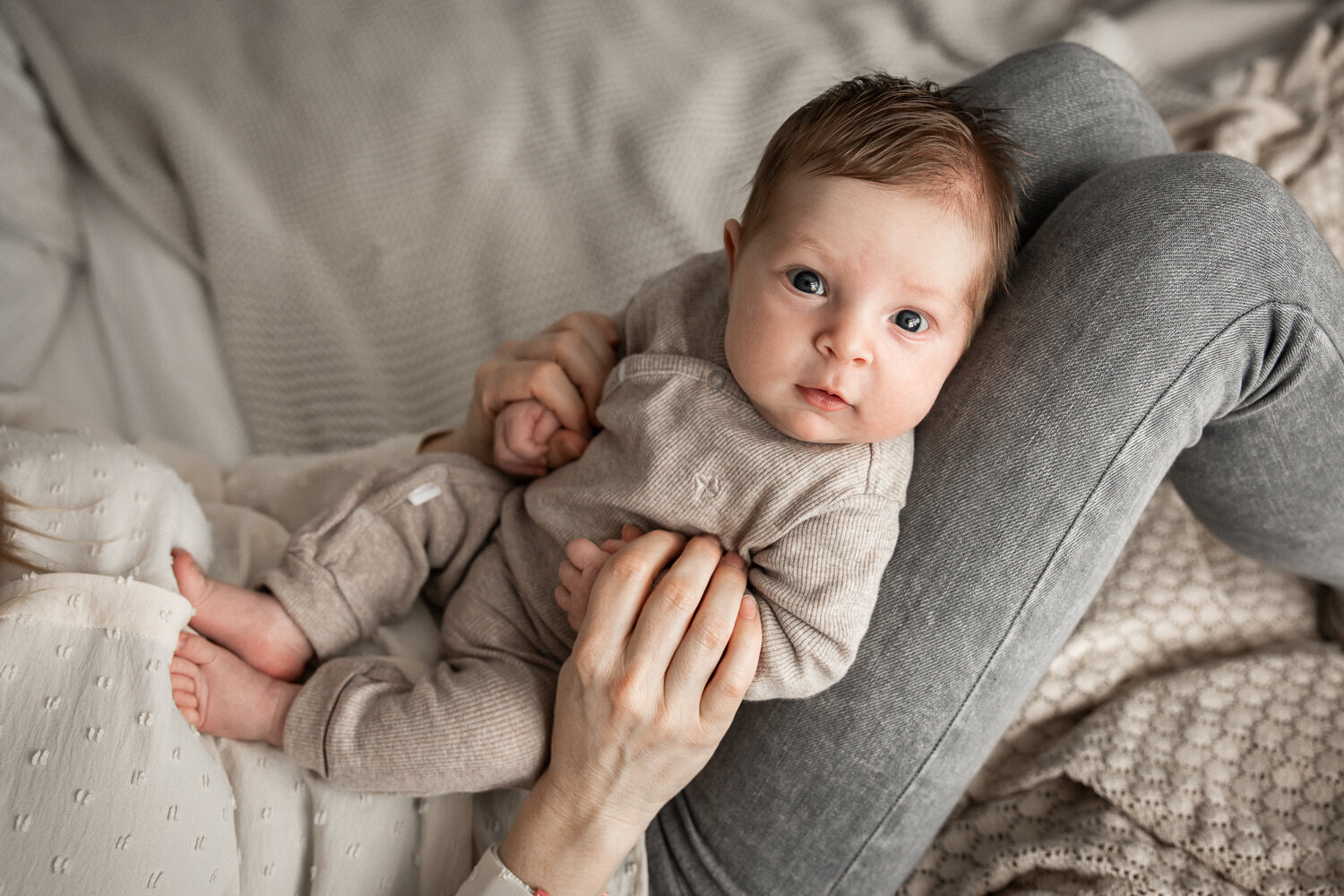 Newborn baby op schoot bij moeder tijdens een fotoshoot op bed thuis