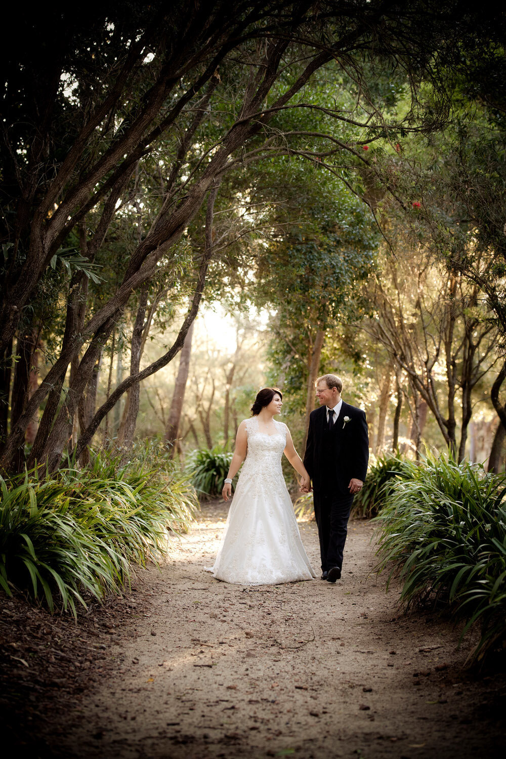 wedding couple holding hands walking down wooded path