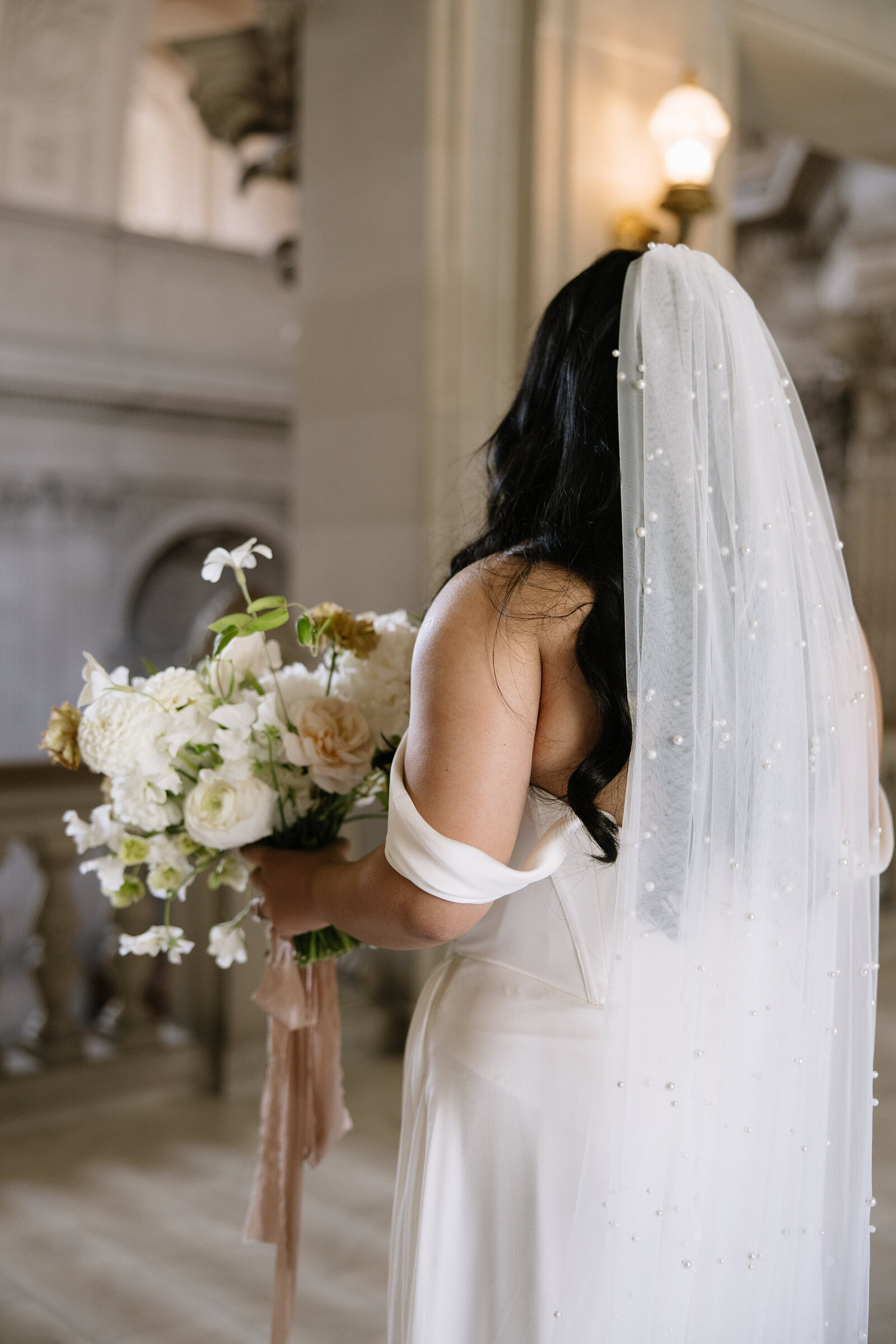 Close up portrait of bride with pearl veil and bouquet in City Hall