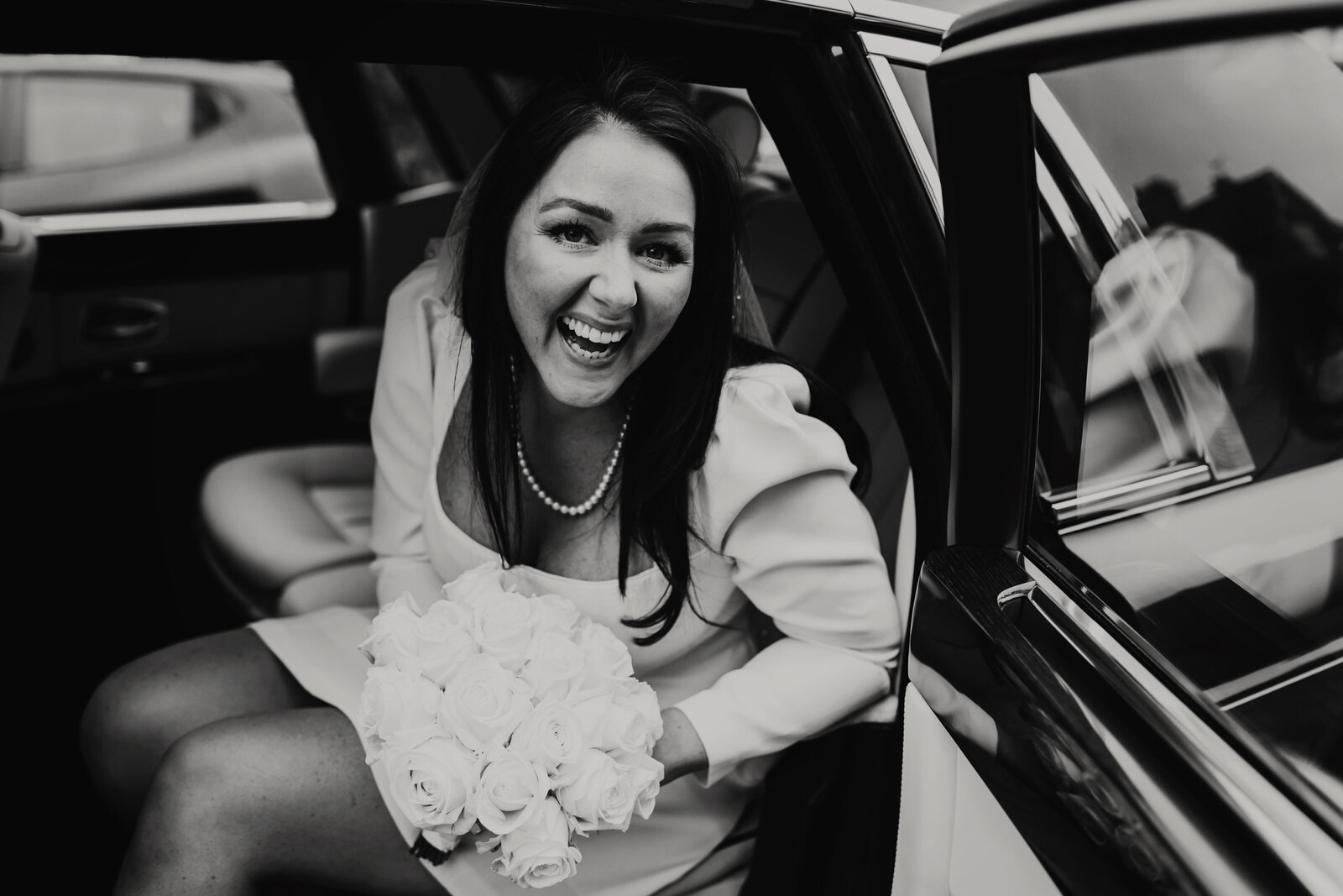 Bride exiting wedding car black and white image at a London Wedding