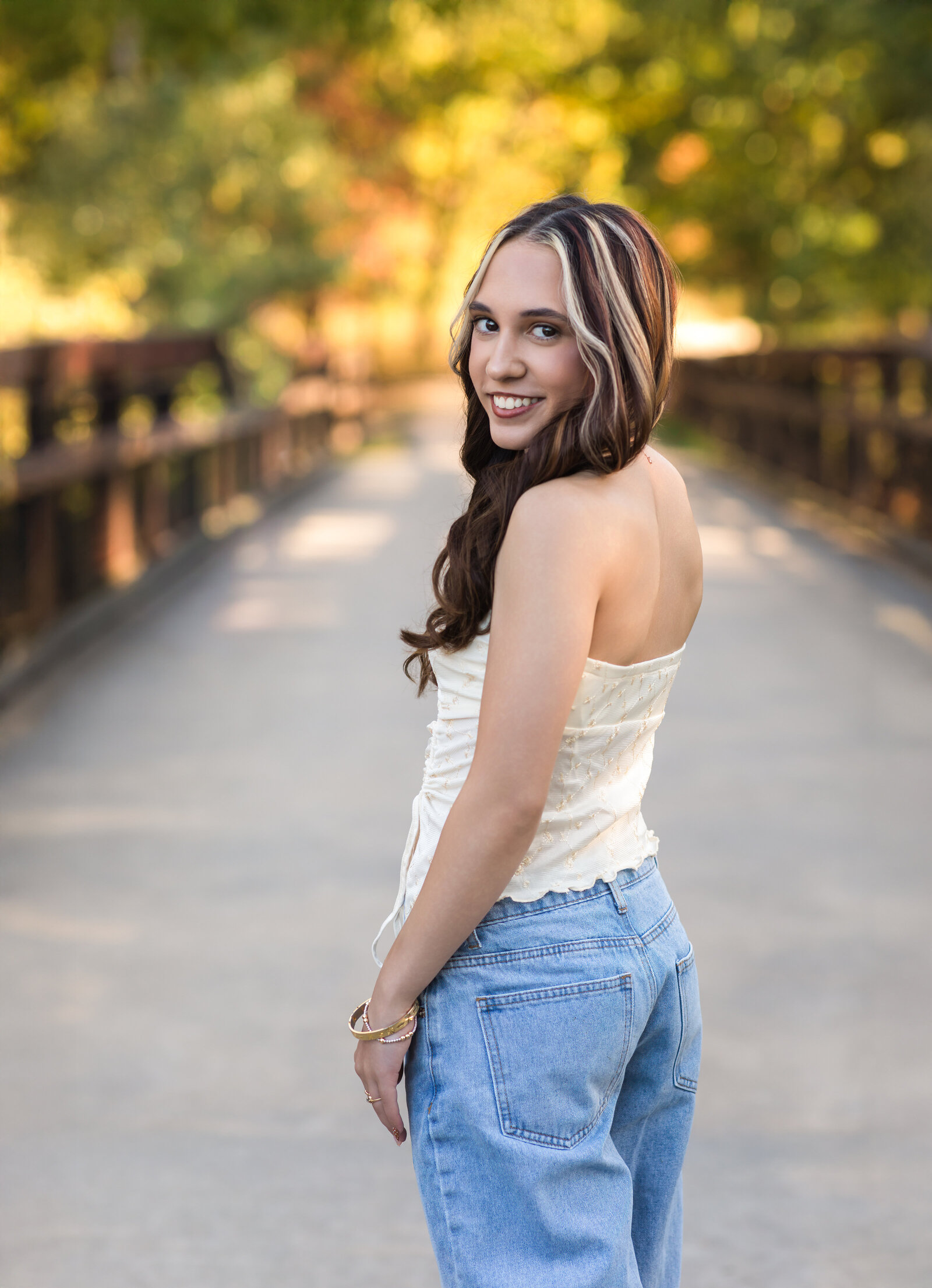 senior girl in tank top and jeans posing in park for senior photos