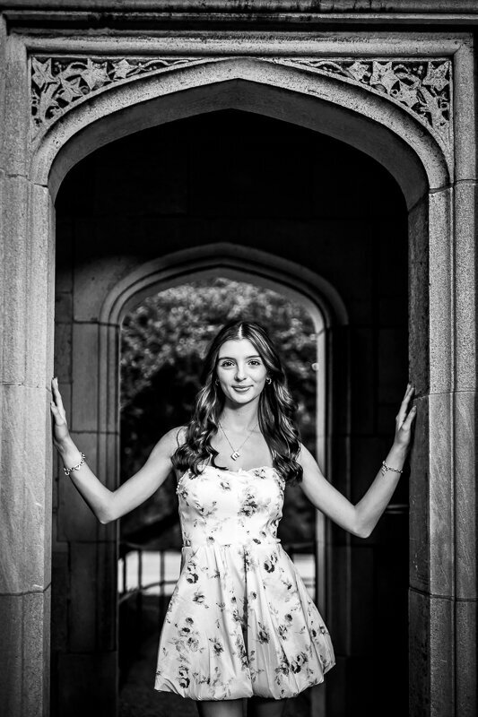 This classic black-and-white image features a senior from North Catholic high school posing between a carved antique archway at the mansion.