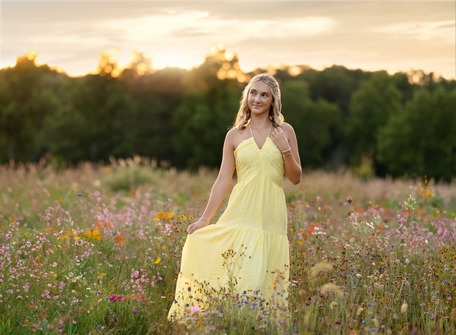 Senior photo of girl spinning around in yellow dress in a wildflower field in Atlanta, GA. Graduation photos taken by Jenni Nikki Photography in Atlanta, GA