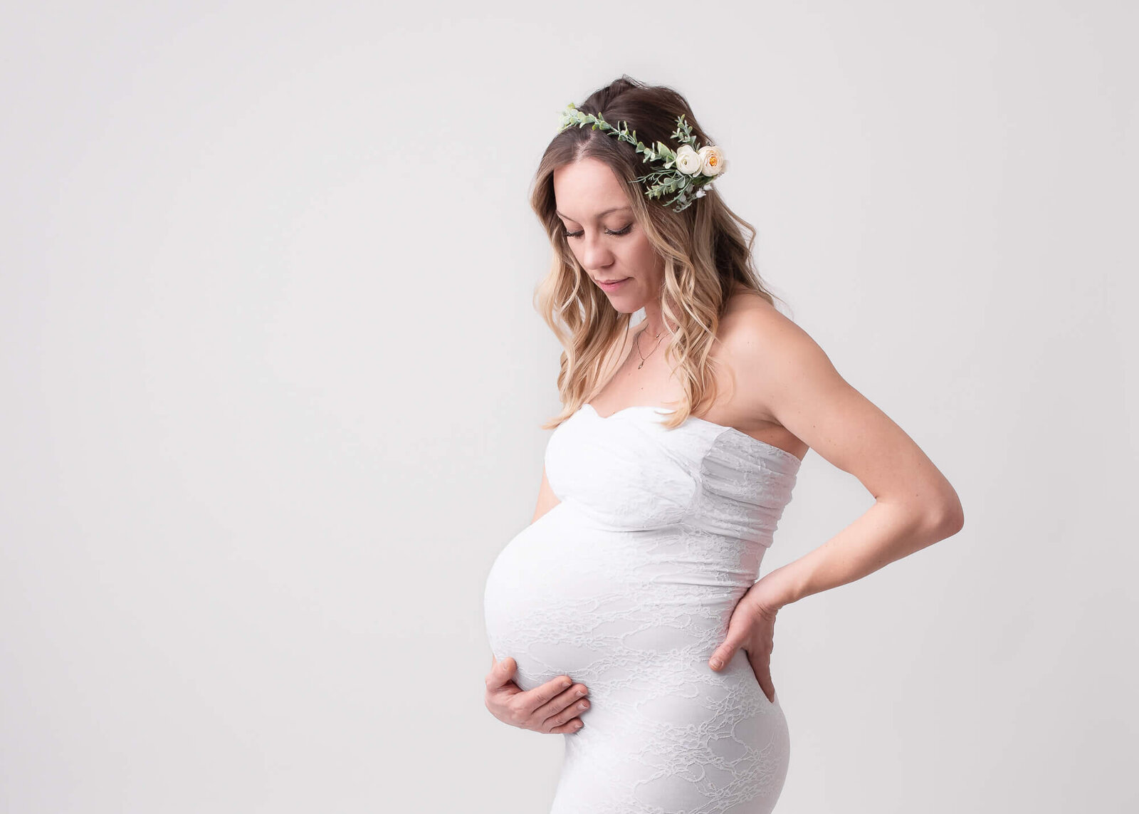 modern studio maternity portrait, woman holding her pregnant belly