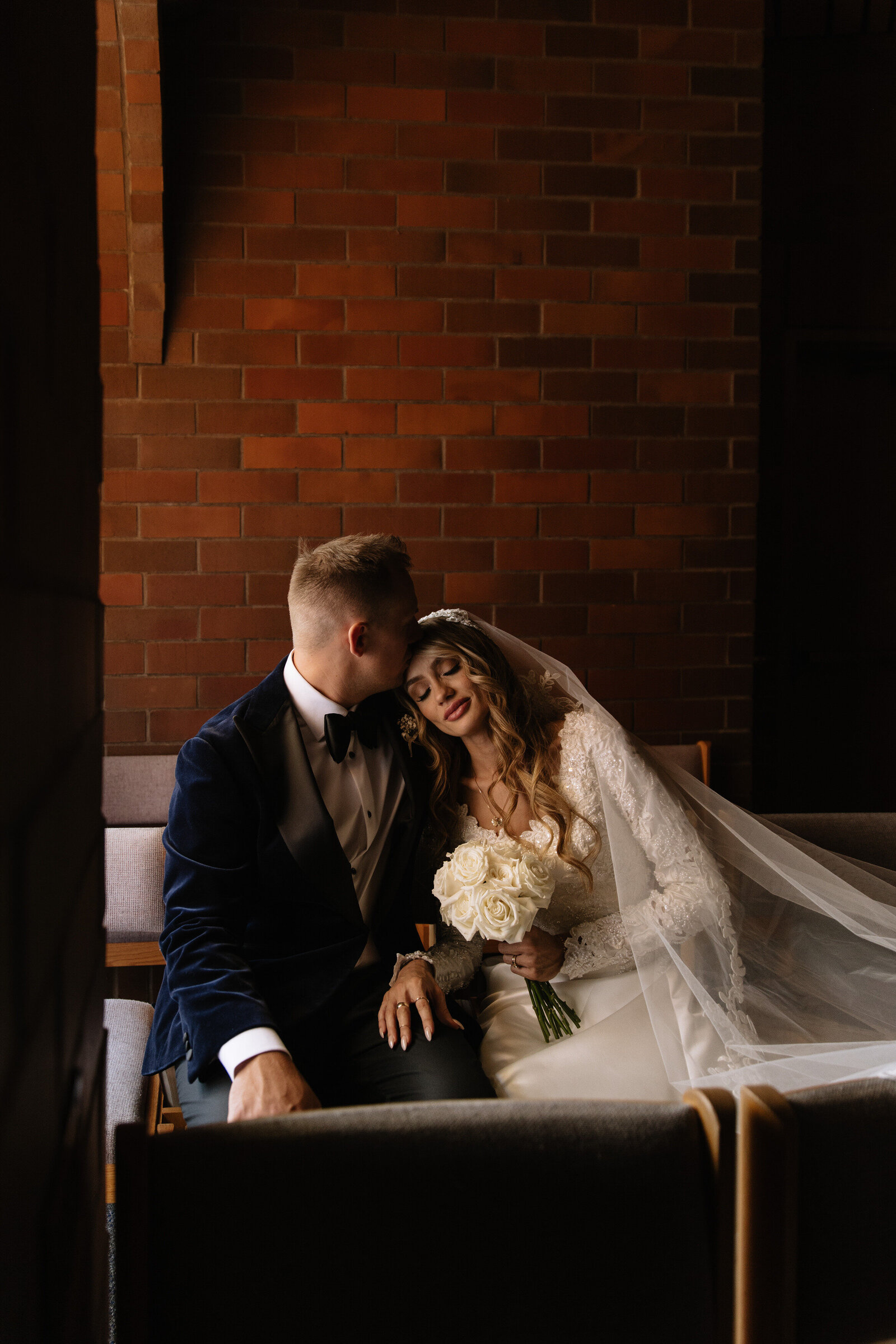 Groom kisses bride's forehead during intimate moment in Idaho Catholic church wedding