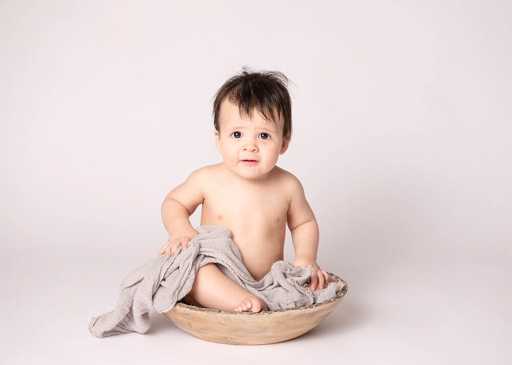 little-boy-sitting-in-prop-with-beige-wrap