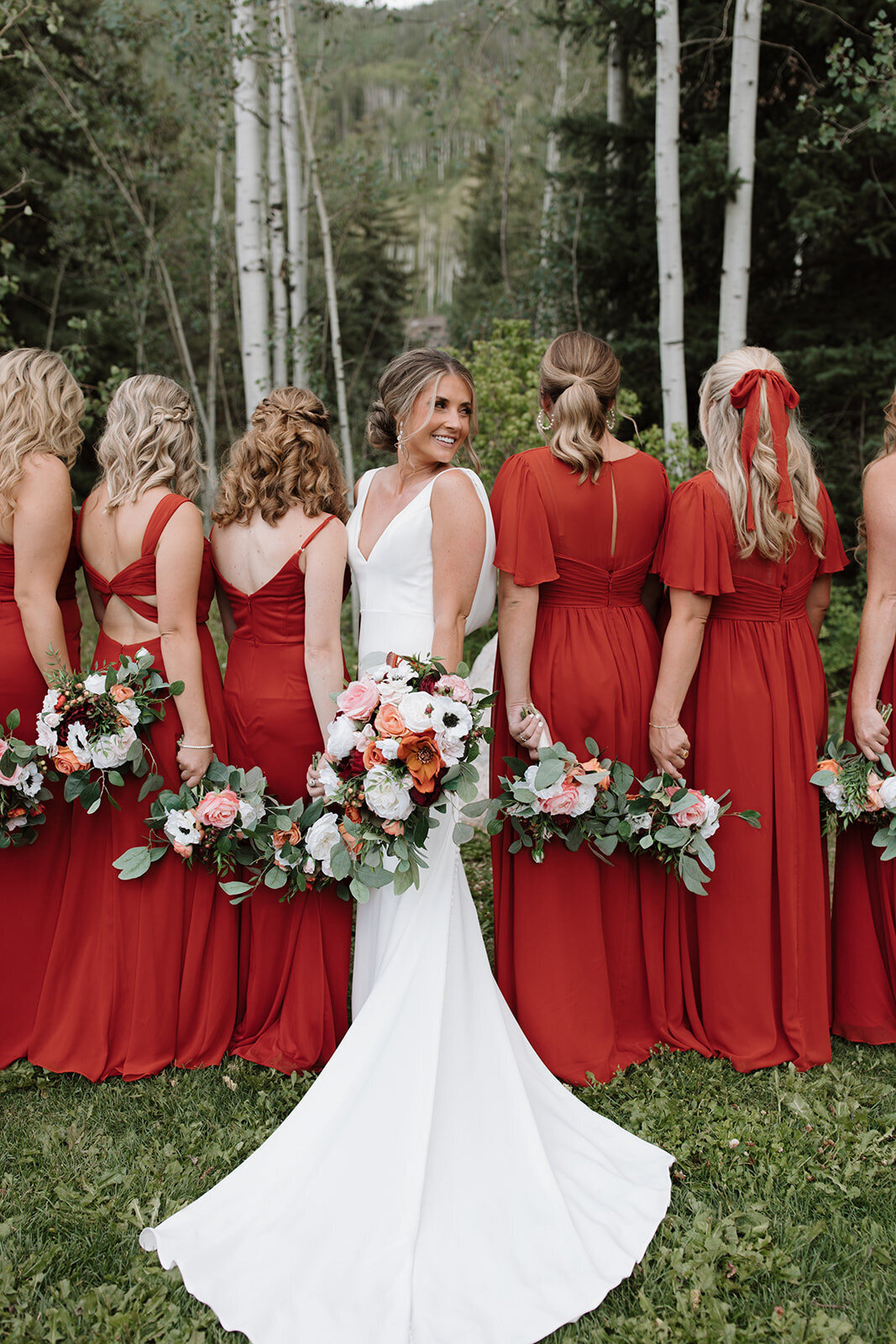 Bride wearing her elegant wedding dress and holding her floral bouquet while bride's maids facing an opposite direction also holding their floral bouquets