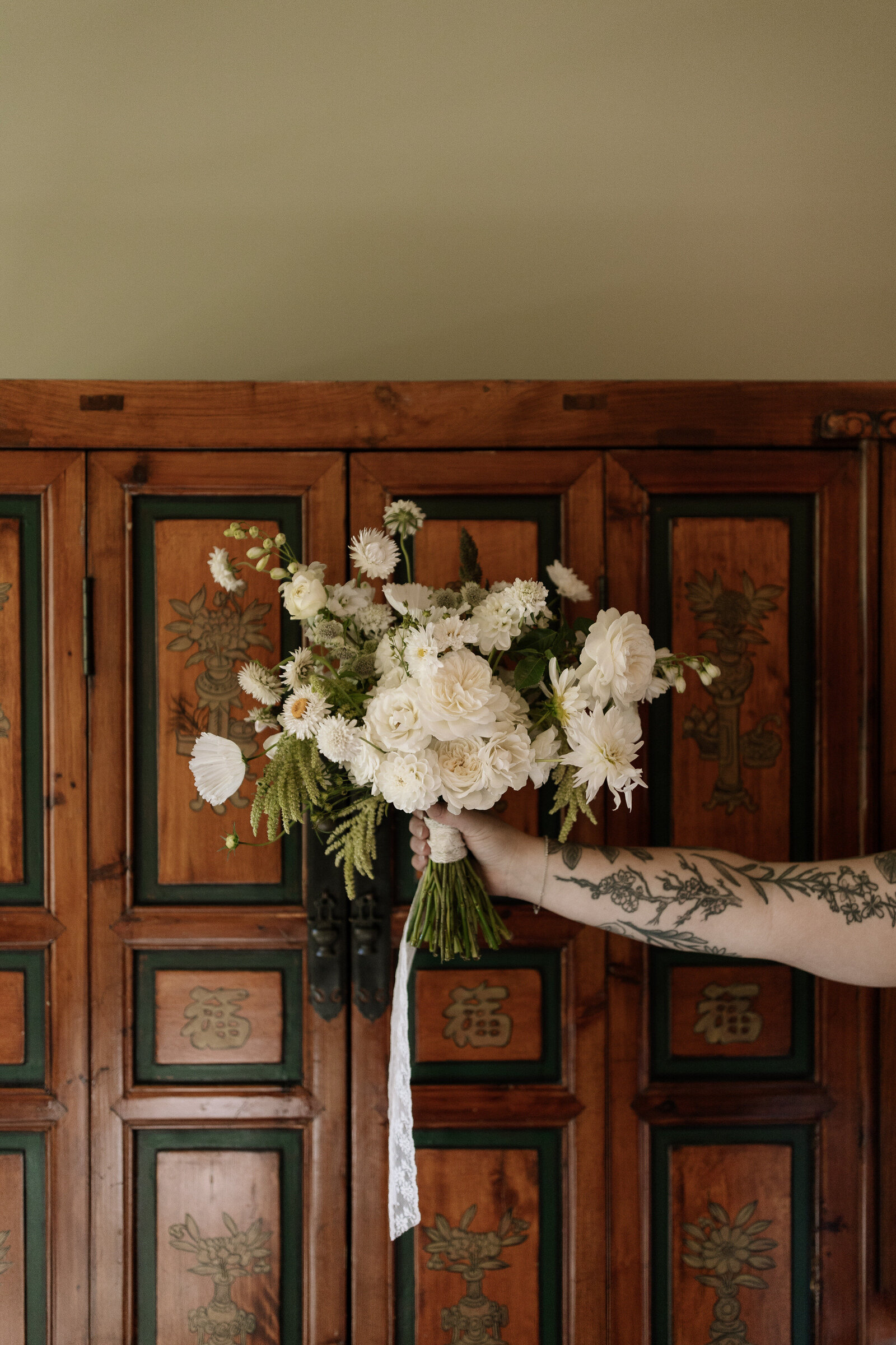 Detail photo of bride holding bouquet in front of wardrobe in getting ready suite