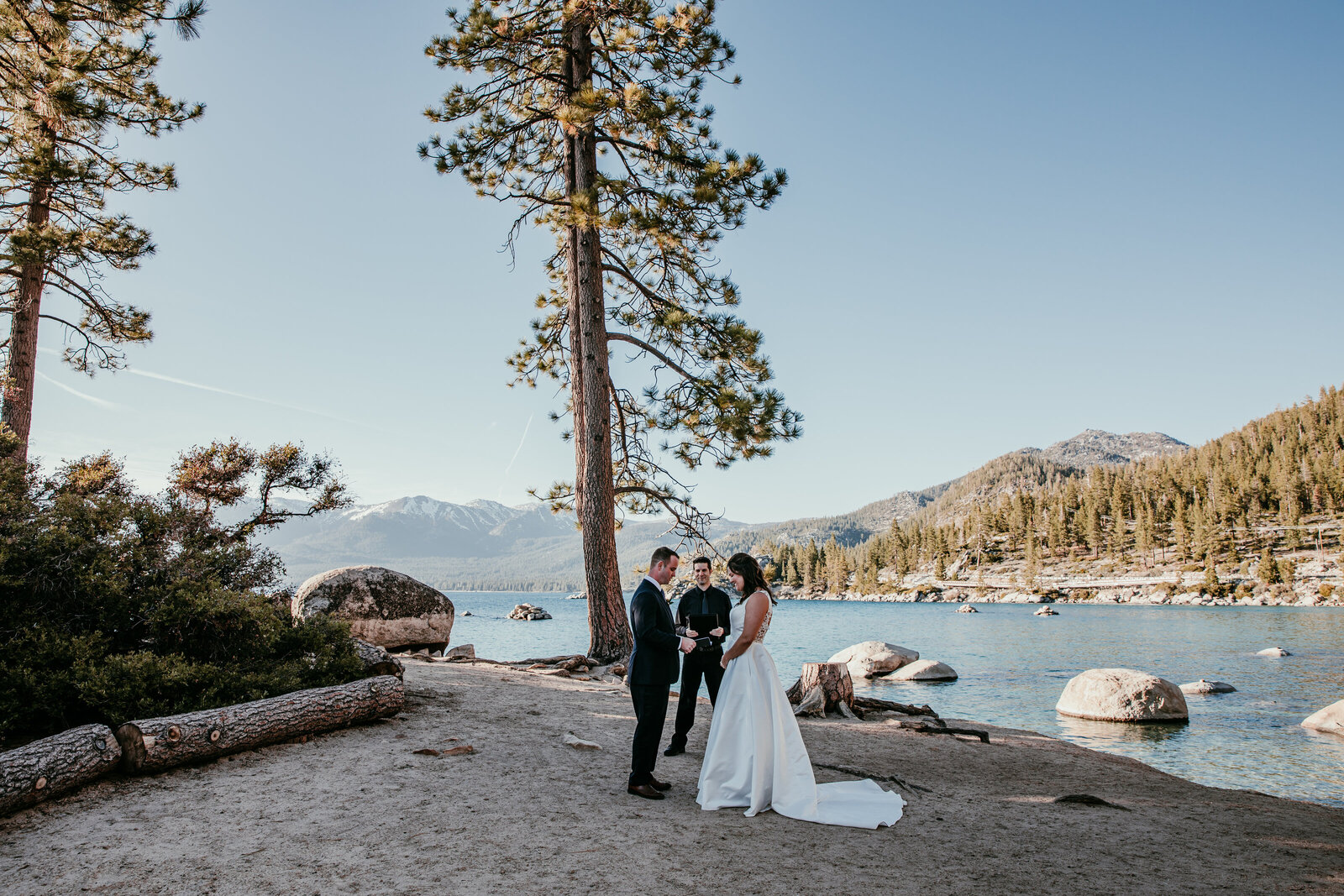 Elopement ceremony at Sand Harbor in Lake Tahoe, with a couple exchanging vows under tall pines beside the clear blue water and mountain views.