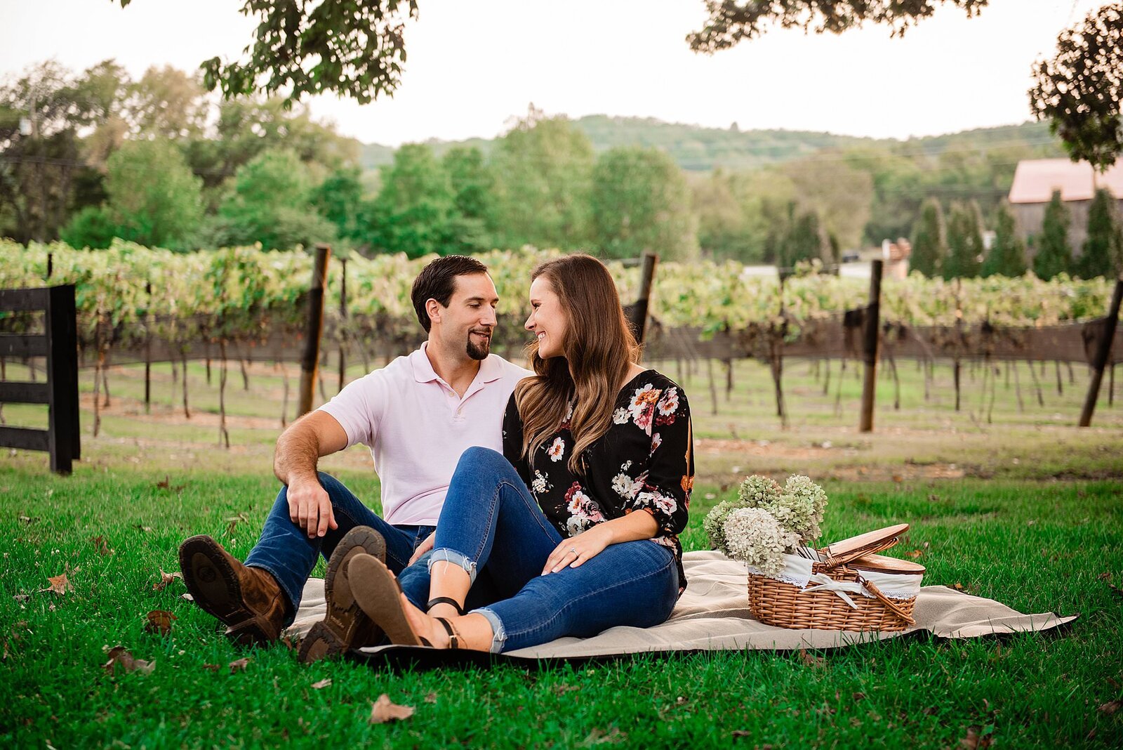 Couple having a picnic in the vineyards at Arrington, picnic basket and blanket on the ground