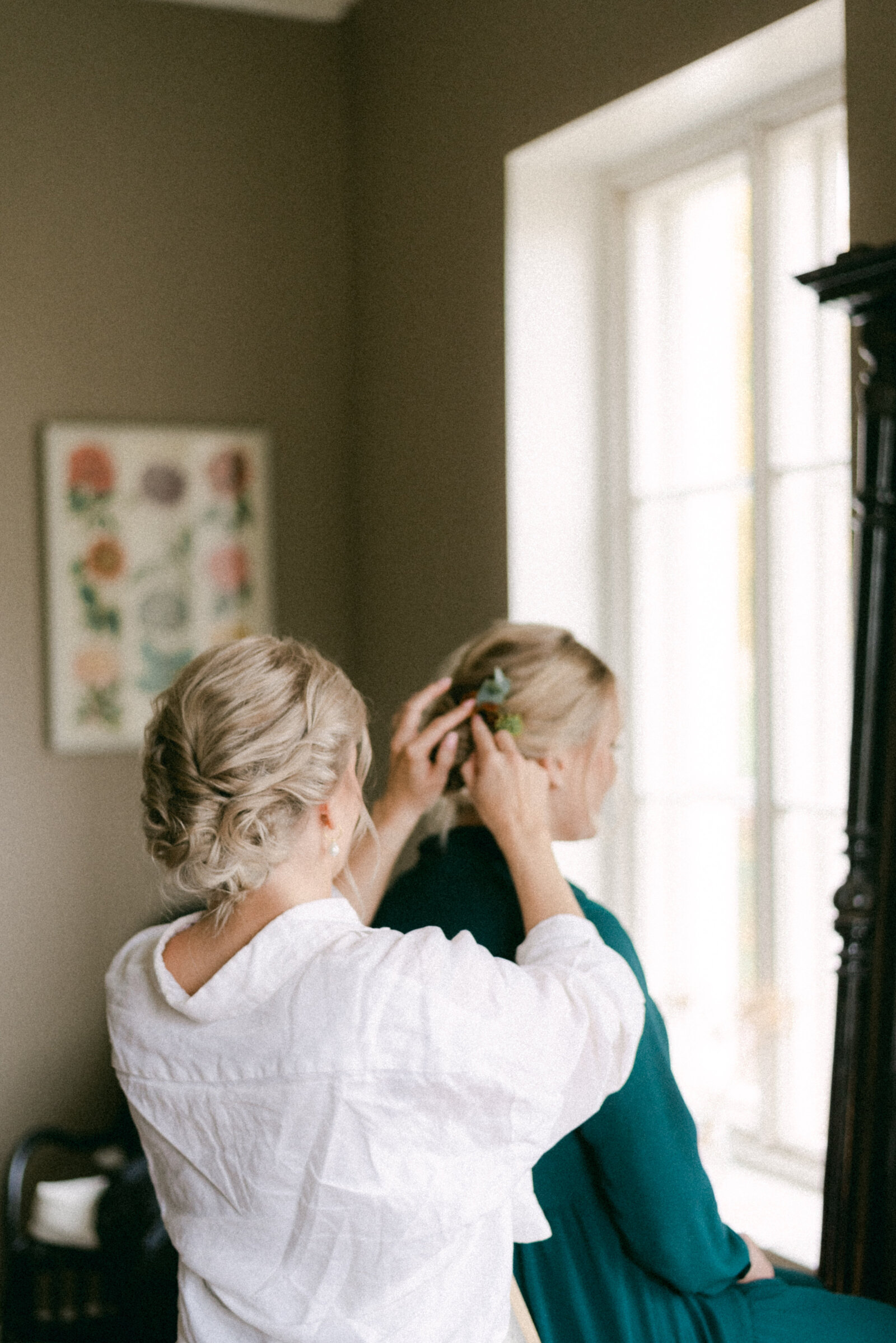 A documentary wedding  photo of the bride putting flowers on her bridesmaid's hair in Oitbacka gård captured by wedding photographer Hannika Gabrielsson in Finland