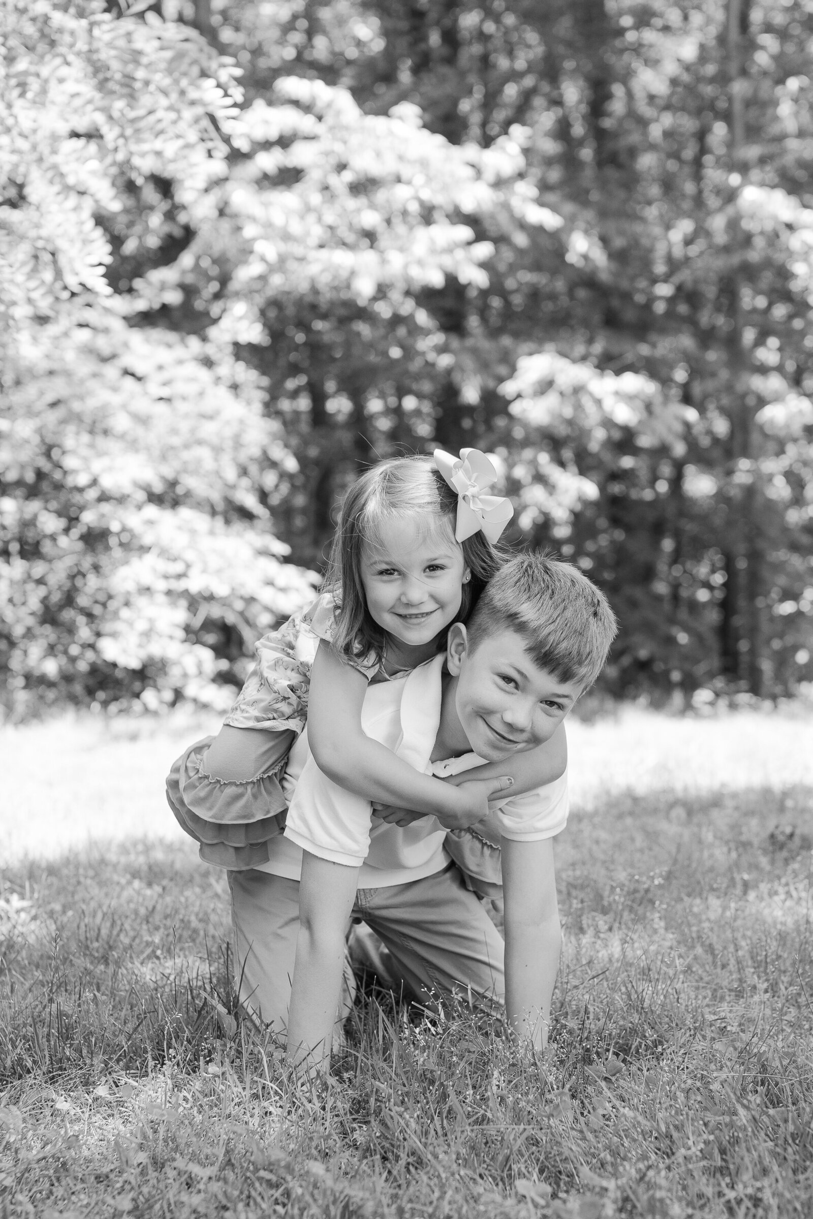 siblings piggy back playing in grass