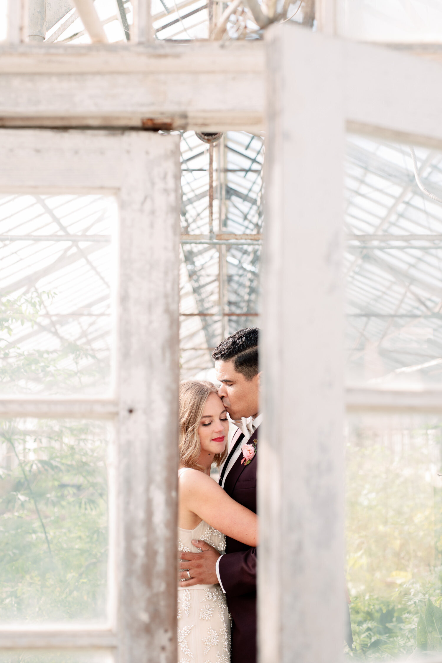 Bride and groom embrace in the greenhouse at Dos Pueblos Orchid Farm